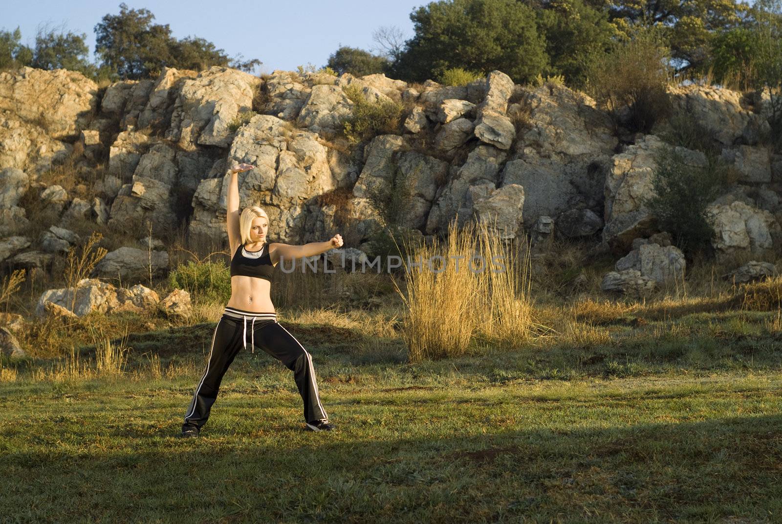 Pretty woman praticing exercise kung fu in natural park with gold light reflector