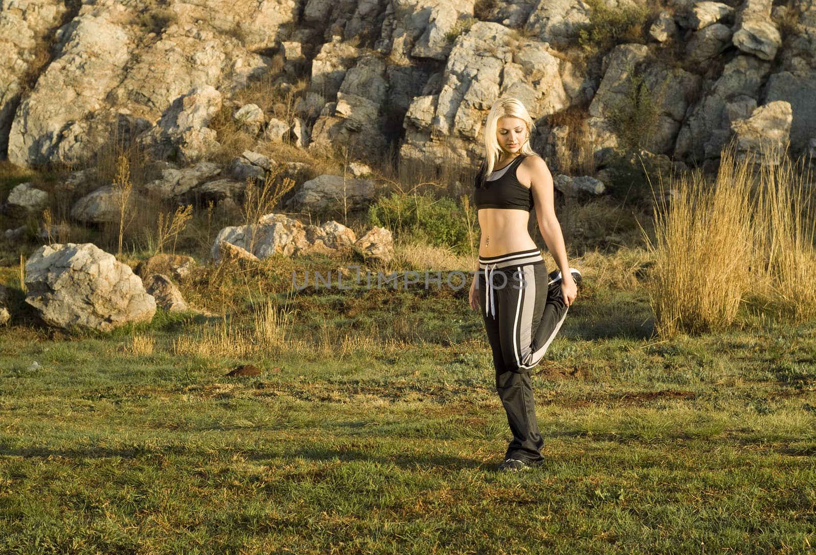 Pretty active woman exercising or stretching leg park with golden light reflector