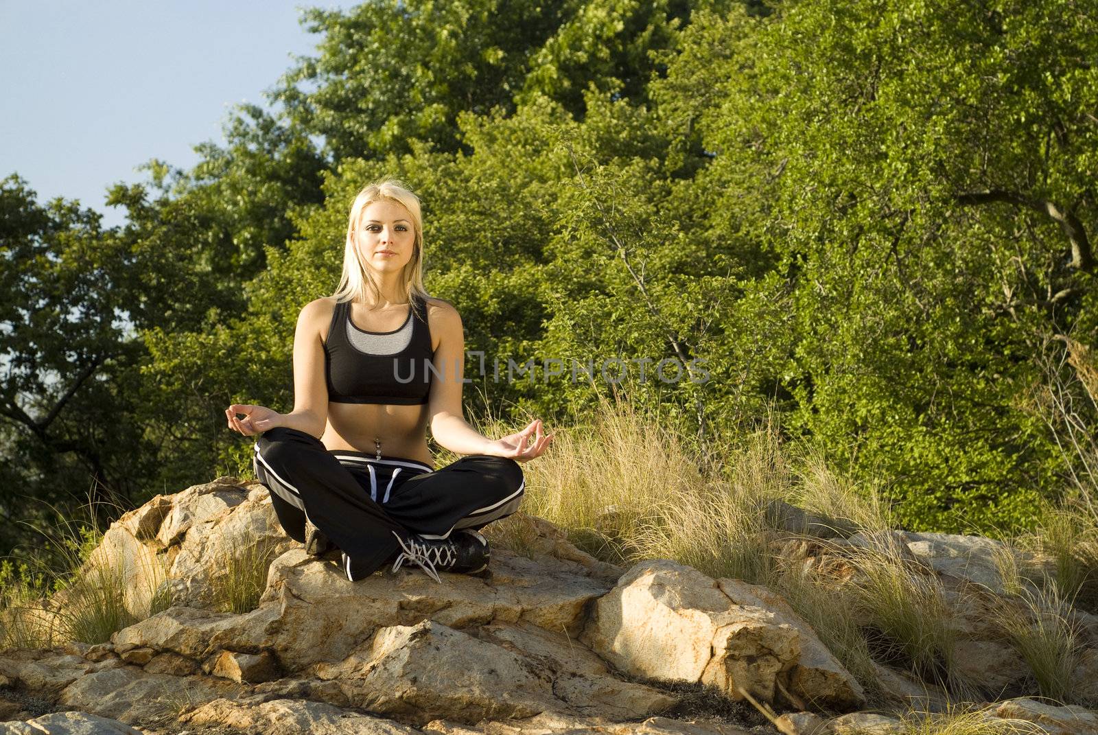 Pretty woman meditating on rock lotus hands with gold light reflector