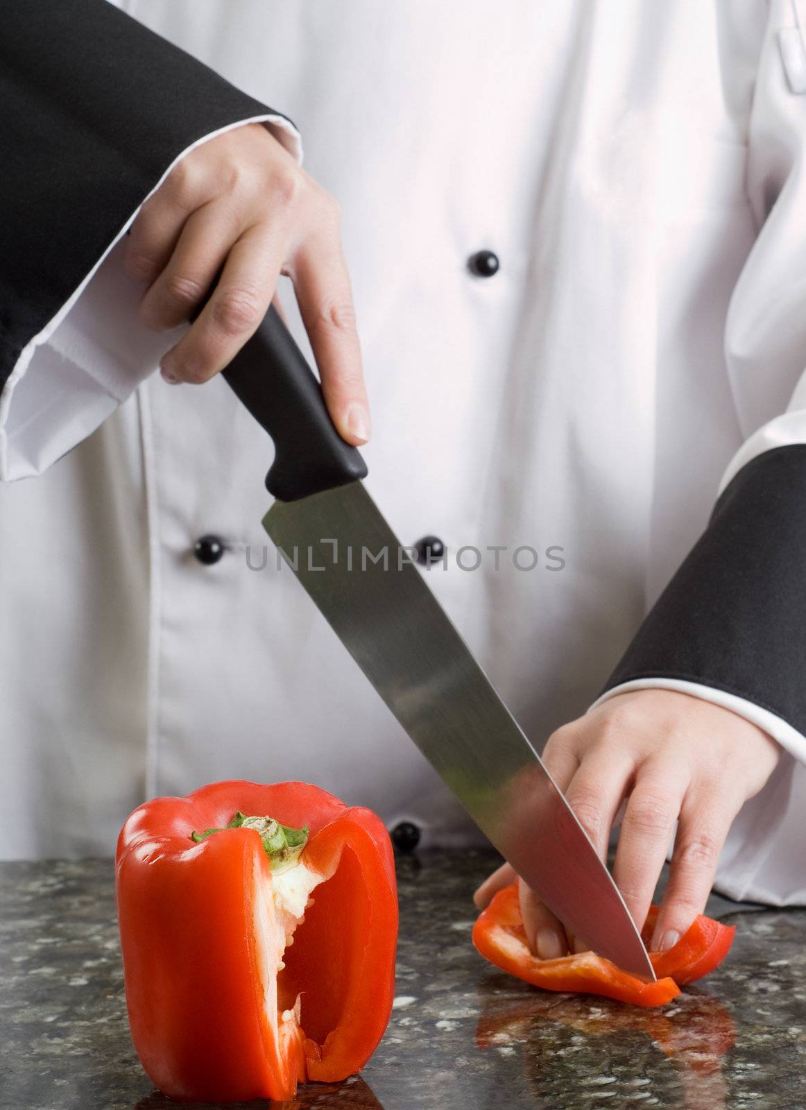 Chef in Black and White Uniform Cutting a Red Pepper Reflecting in Stove Top