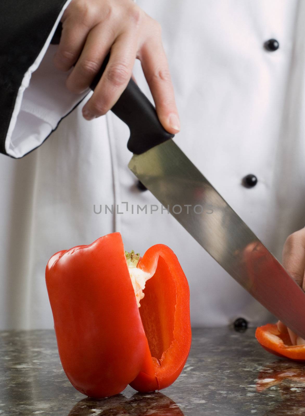 Chef in Black and White Uniform Cutting a Red Pepper Reflecting in Stove Top