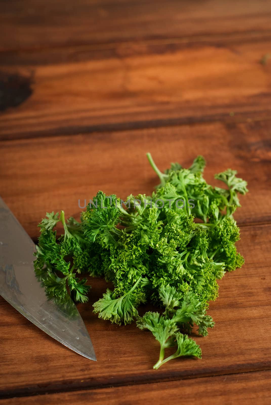Green parsley on wooden chopping board with kitchen knife