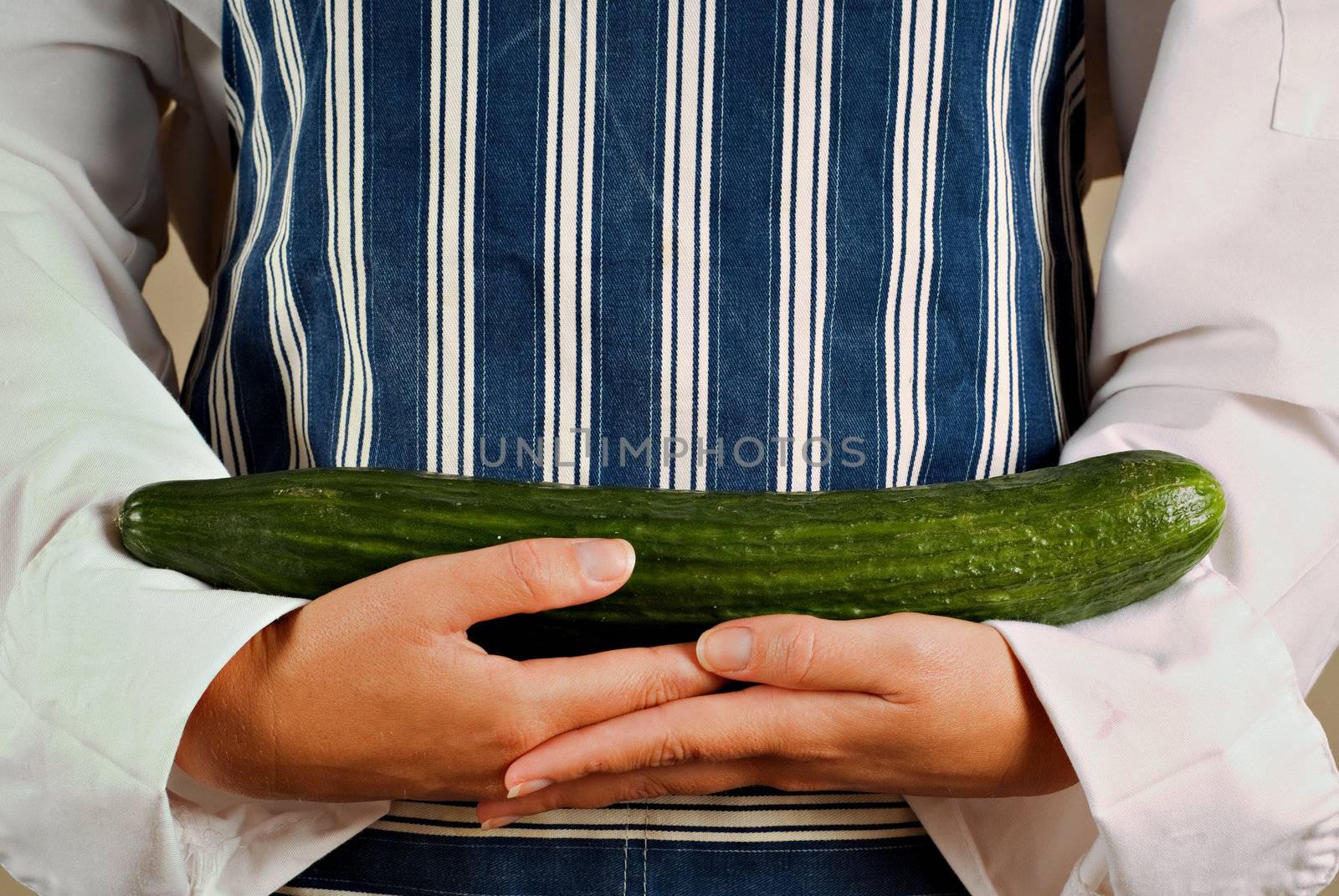Female woman vegitarian chef or cook holding cucumber vegetable in her hands