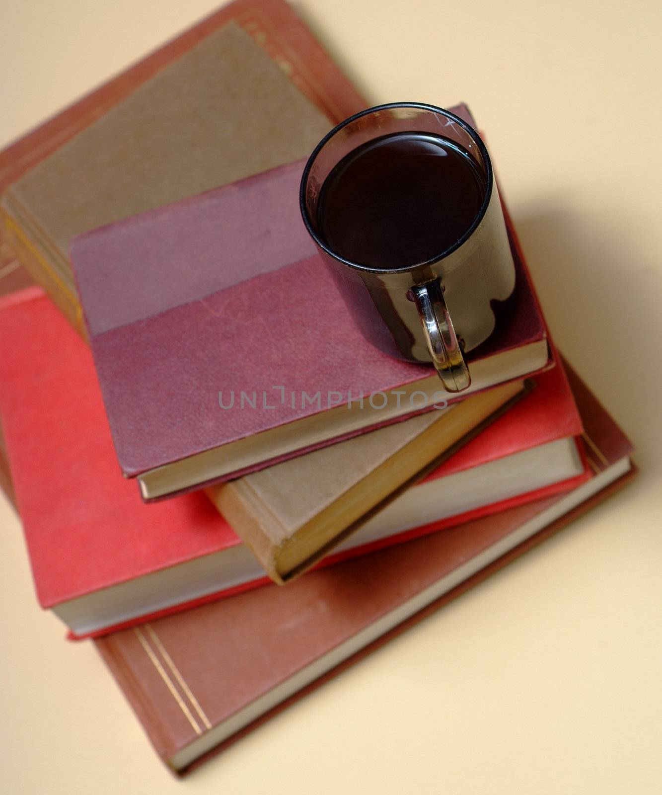 Pile of old books with covers and white pages with red background and a mug or cup of coffee