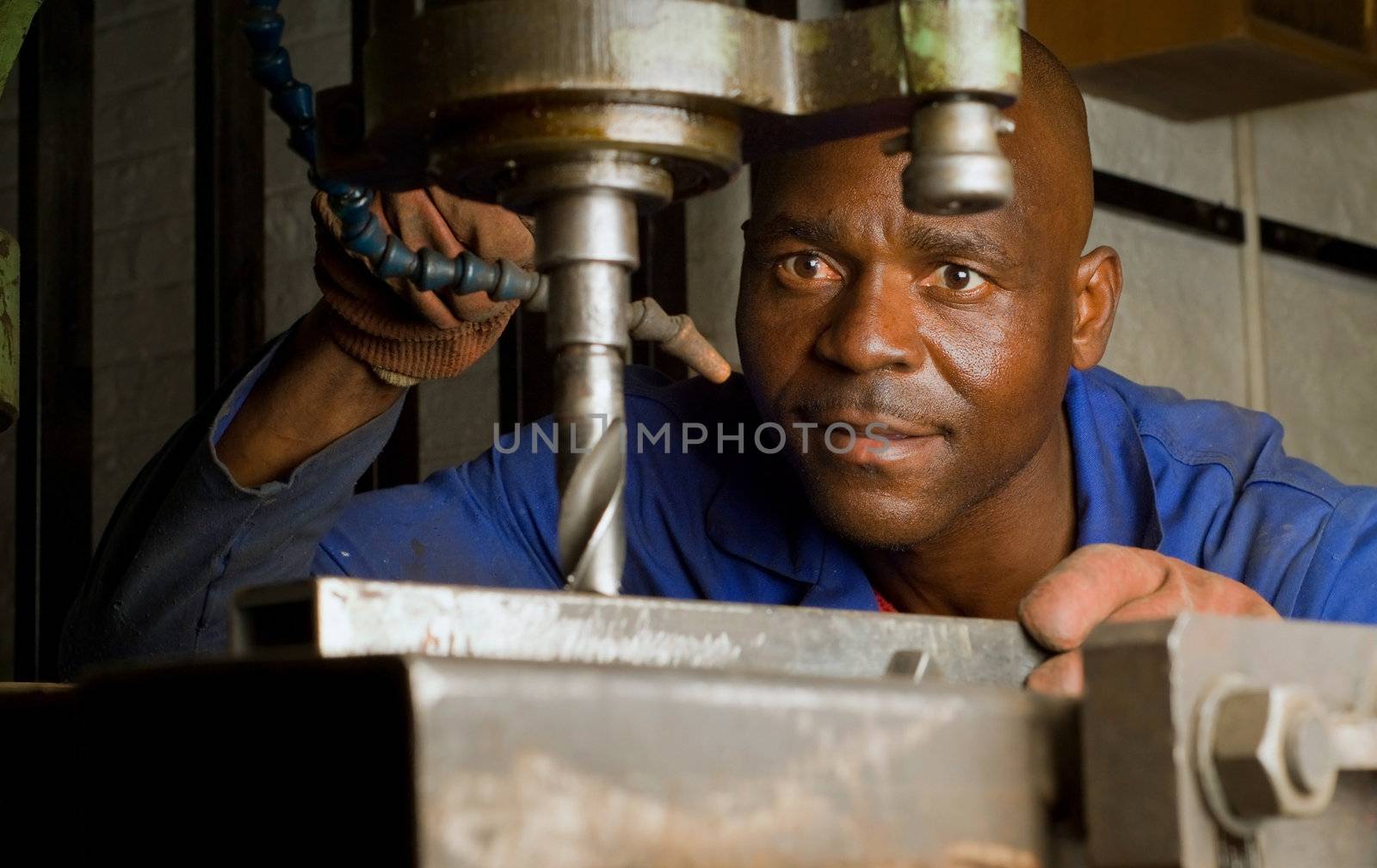 South African or American worker engineer working with industrial drill press