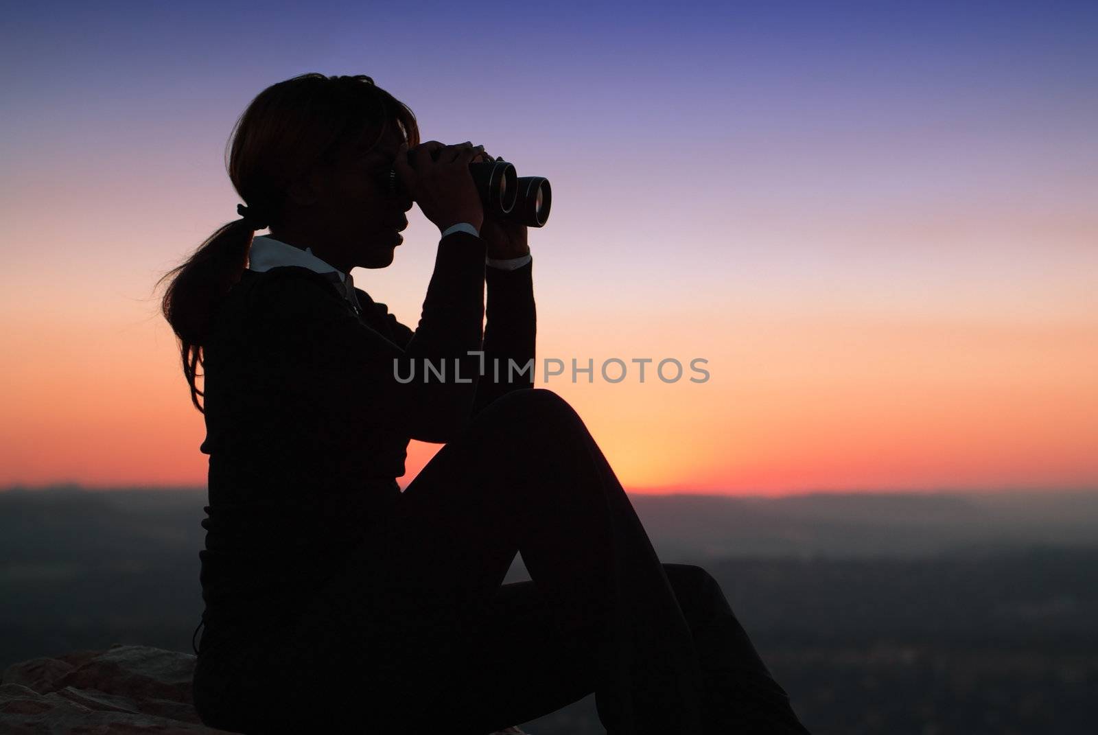 Silhouette of Business Woman with Binoculars Sitting on a Hilltop