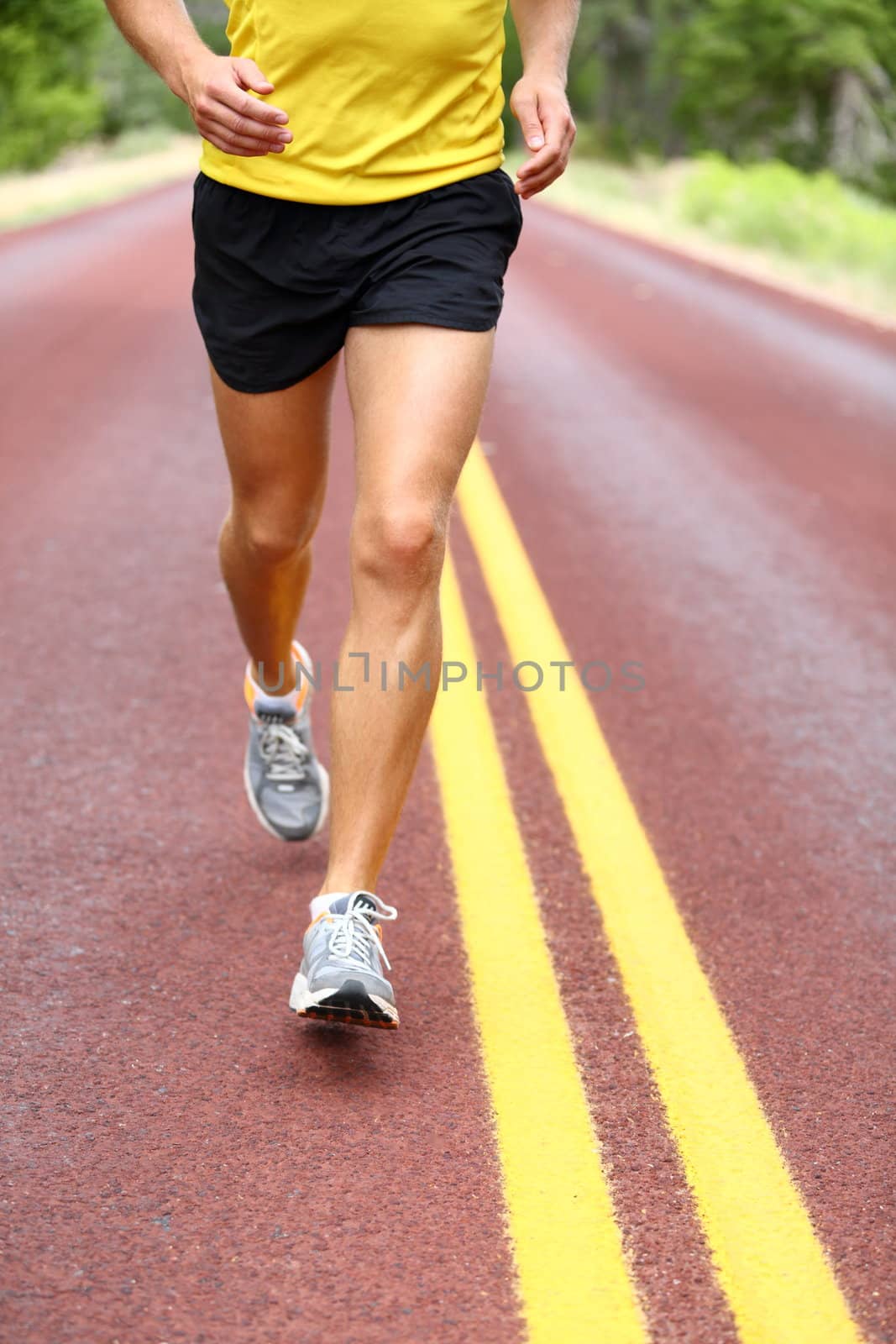 Running man. Runner closeup of running shoes of male legs jogging outdoors on road.