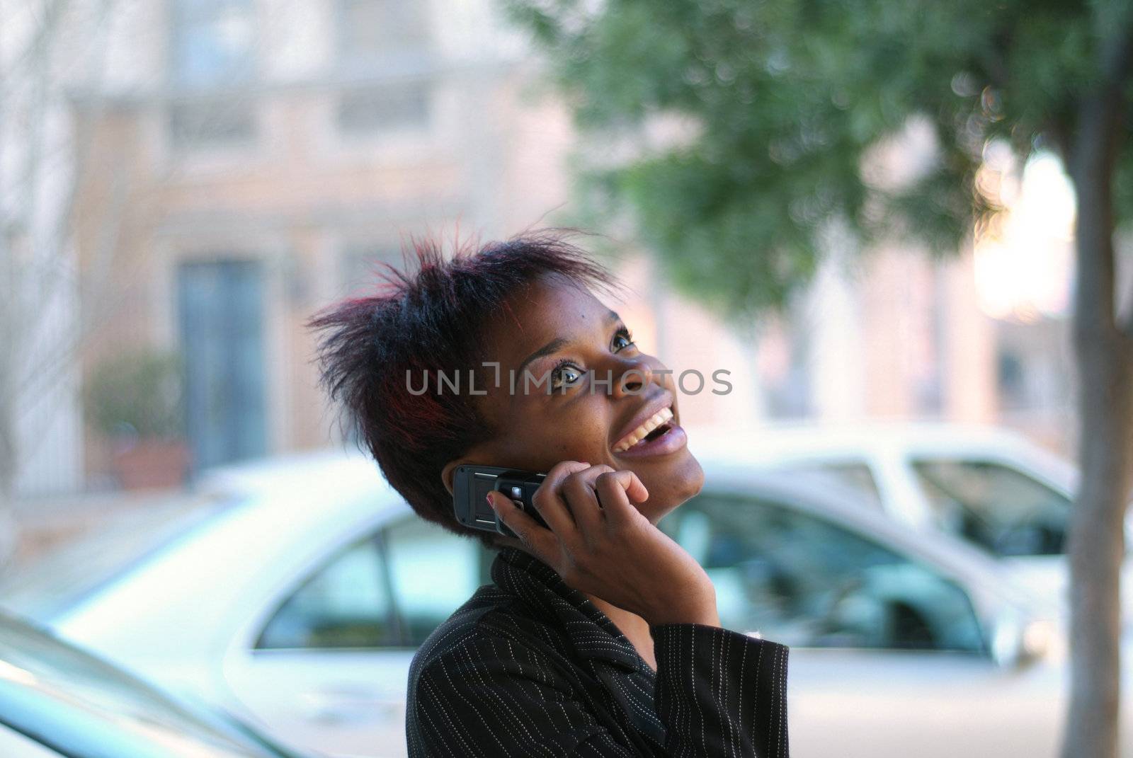 Smiling happy African American businesswoman talking on cell phone in front of new cars - arranging for finance