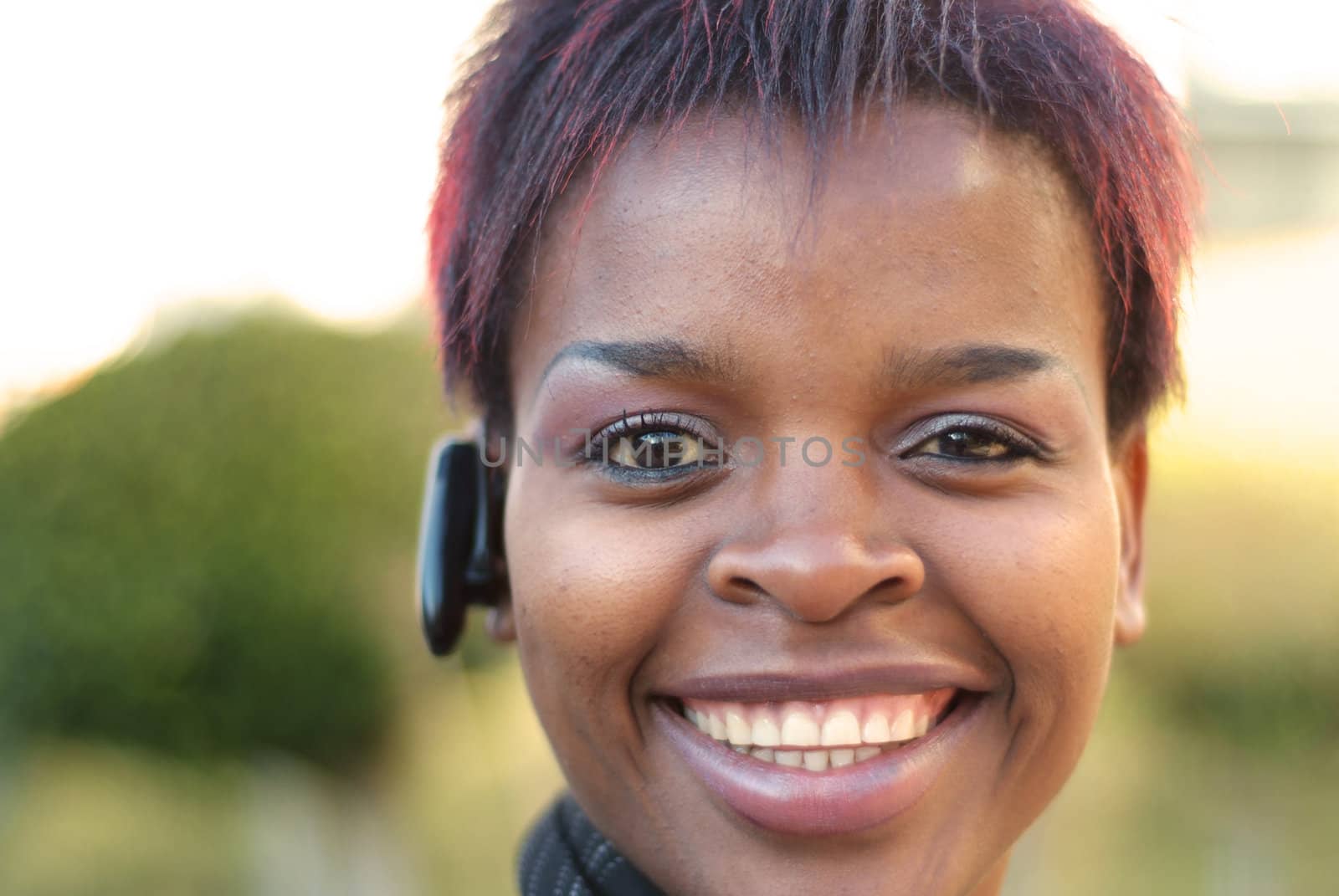 African American businesswoman vertical portrait with bluetooth mobile phone headset - selective focus on left eye