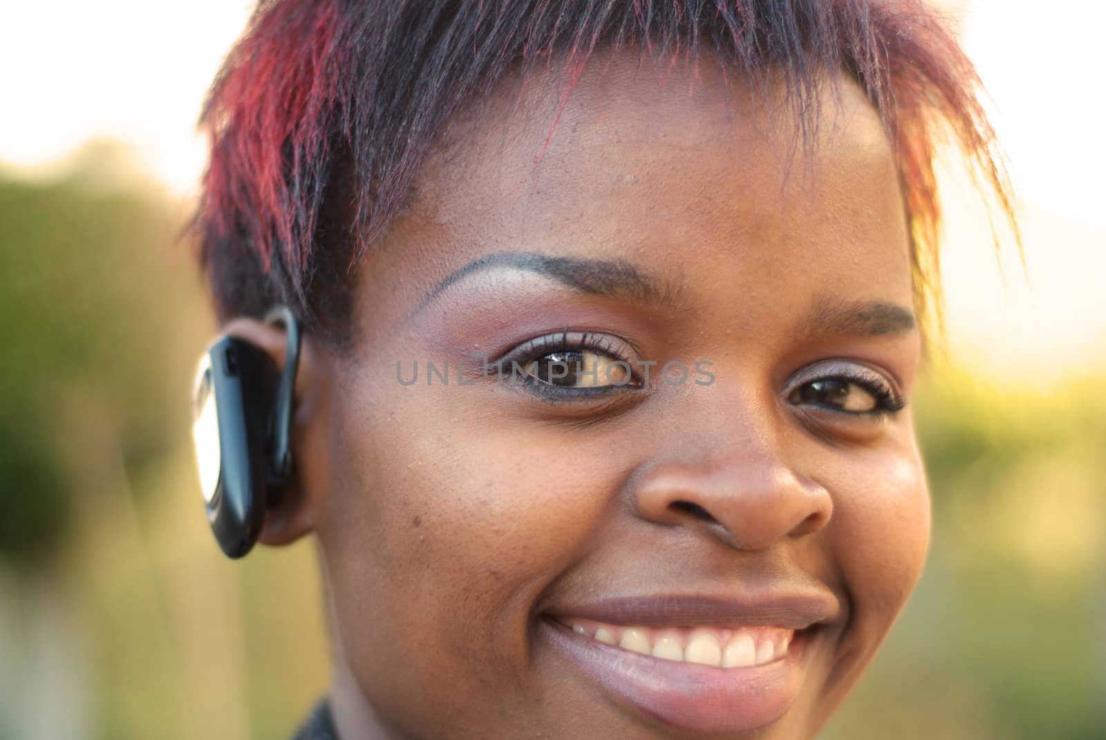 African American businesswoman vertical portrait with bluetooth mobile phone headset - selective focus on left eye