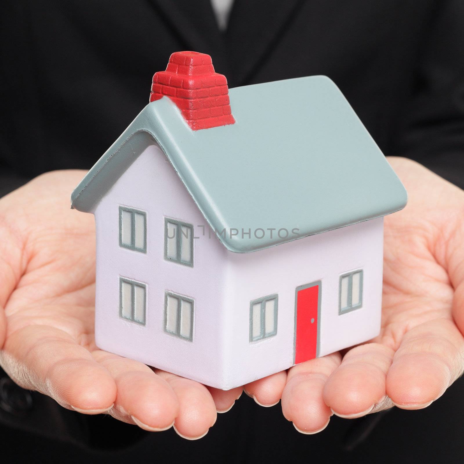 Mini model house and home. Closeup of realtor hands showing miniature model house. New home concept.