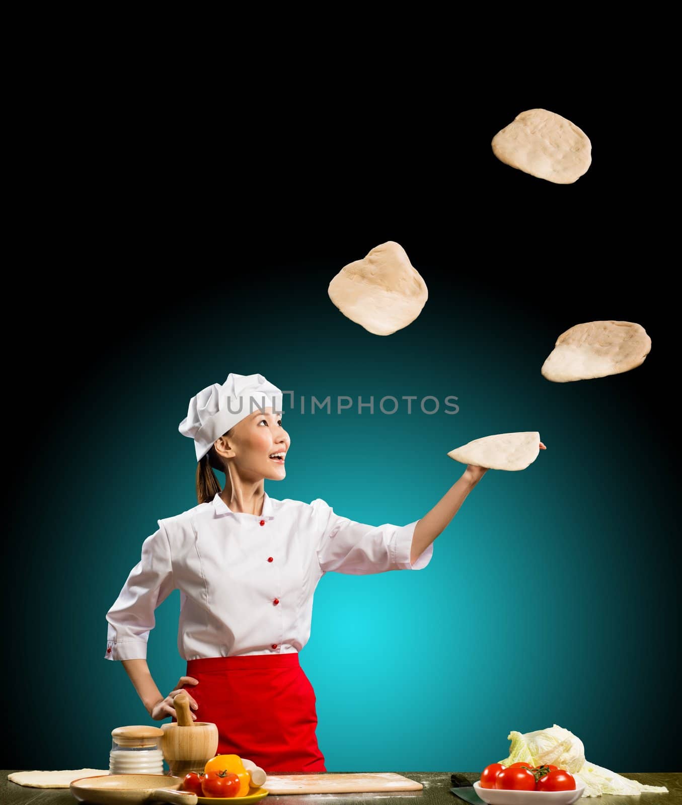 Asian woman chef juggling with pieces of dough for pizza