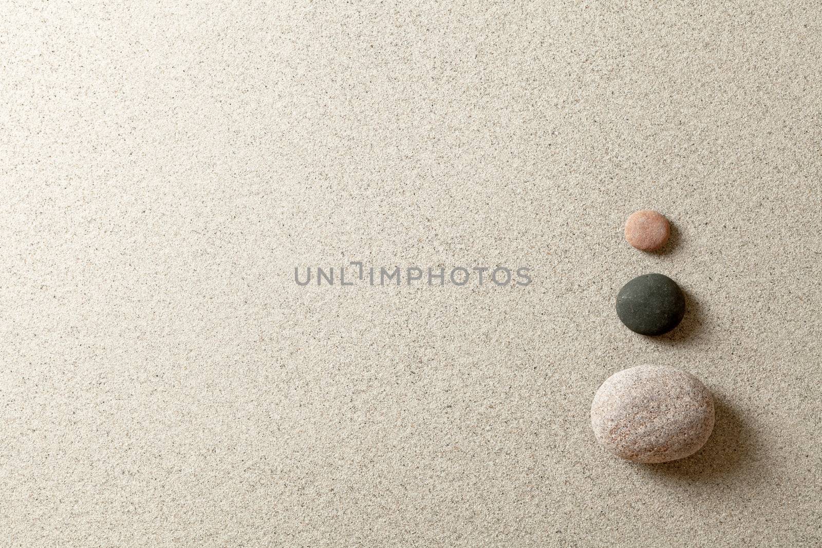 Three colorful zen stones at right side of sand background