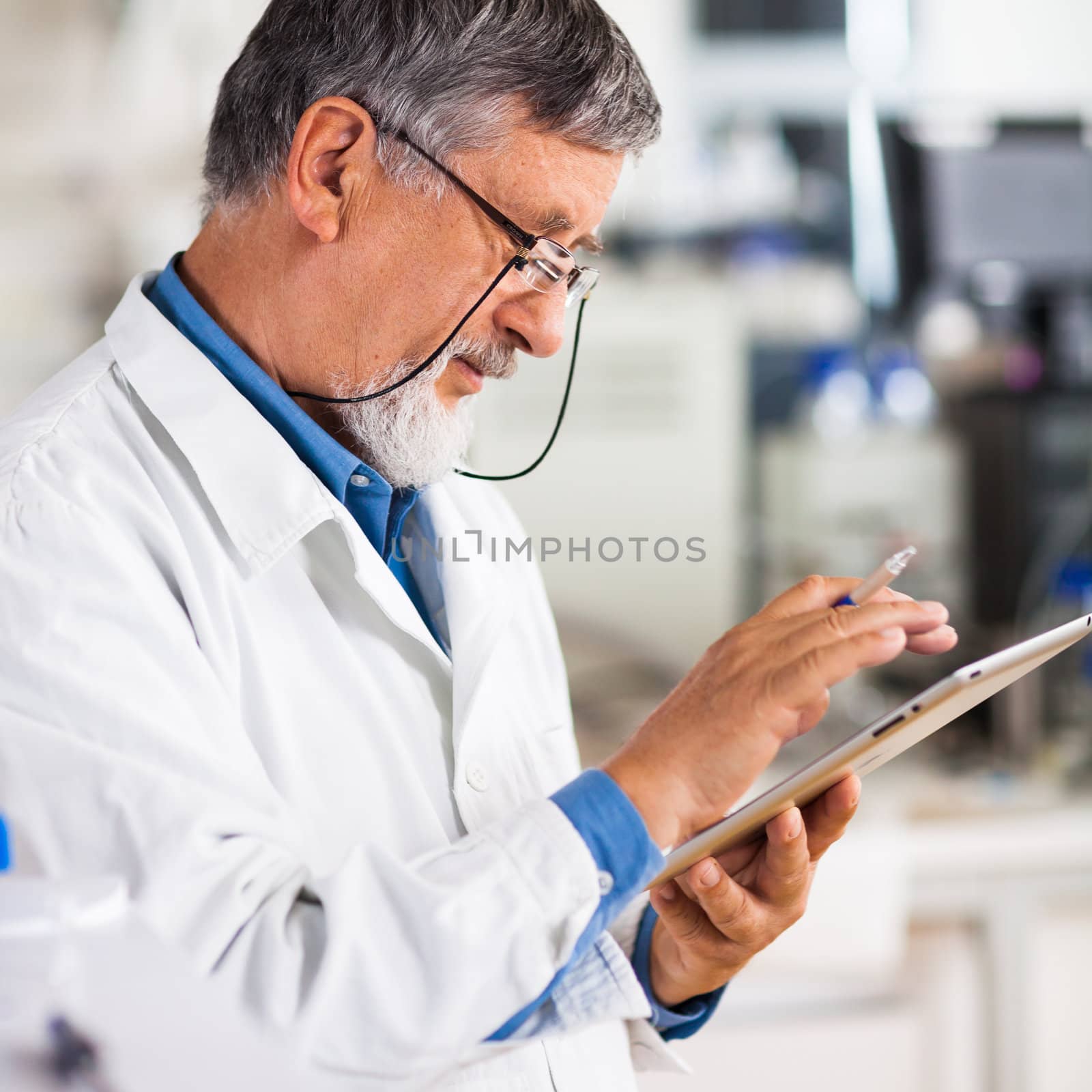 Senior doctor/scientist using his tablet computer at work (color toned image)