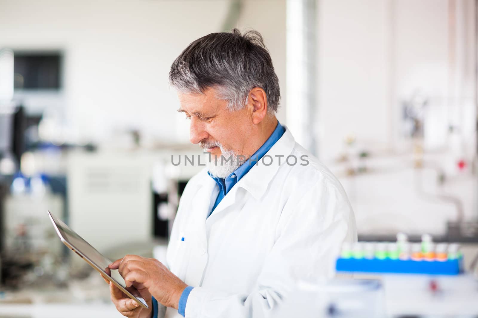 Senior doctor/scientist using his tablet computer at work (color toned image)