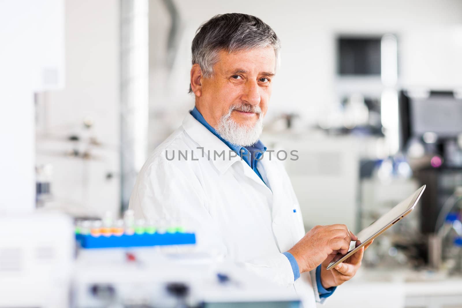 Senior doctor using his tablet computer at work (color toned image)