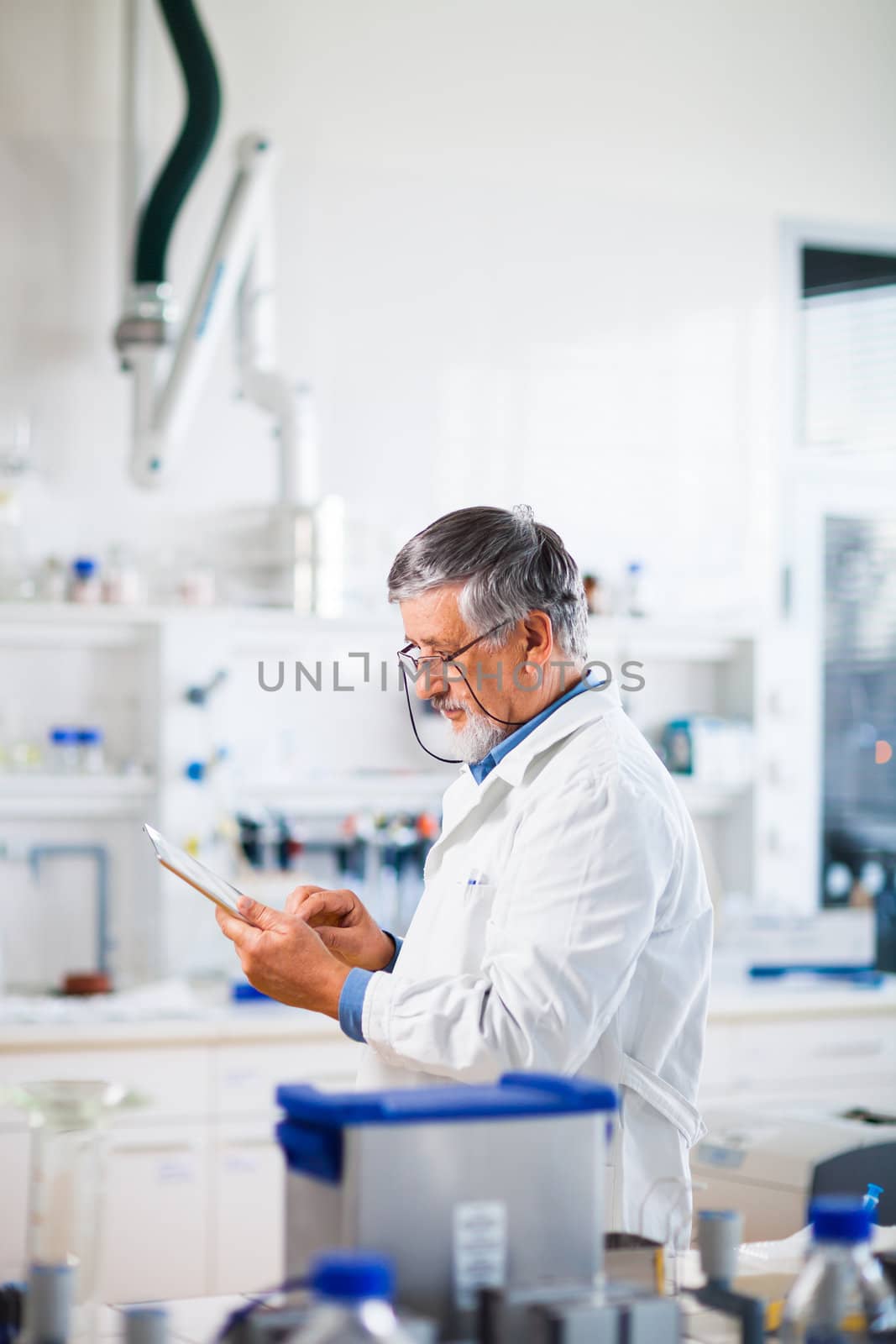 Senior doctor/scientist using his tablet computer at work (color toned image)