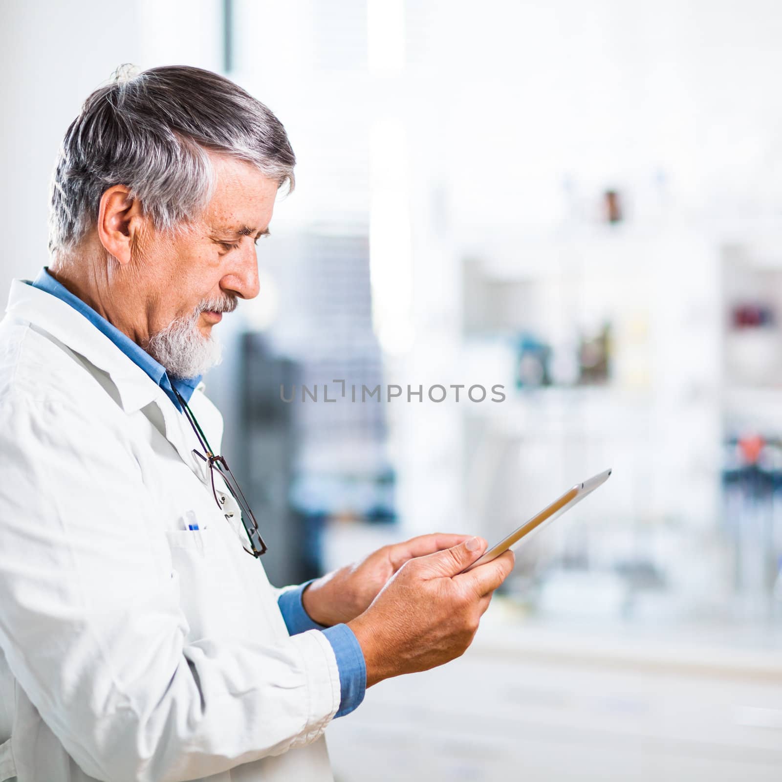 Senior doctor/scientist using his tablet computer at work by viktor_cap