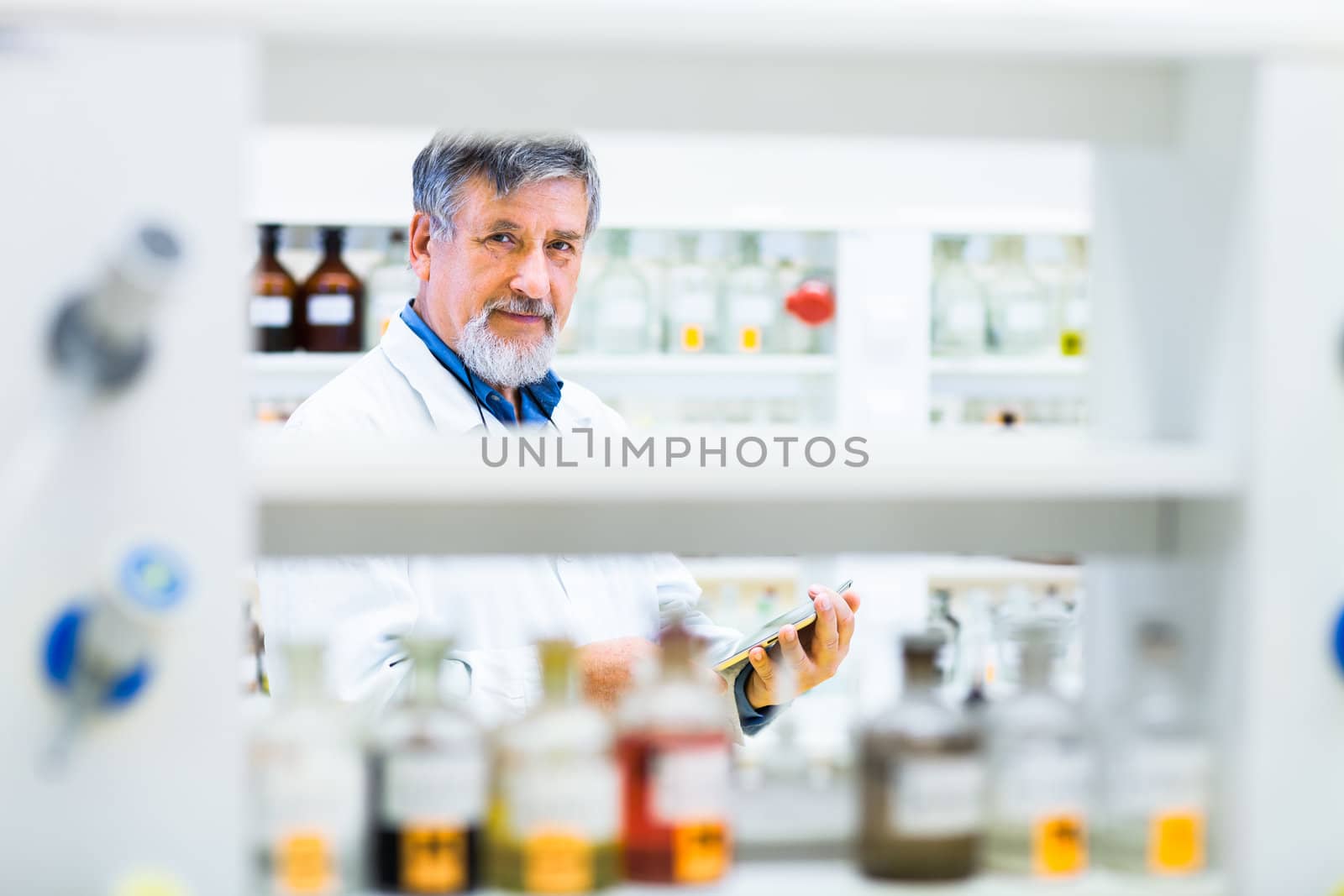 Senior doctor using his tablet computer at work (color toned image)