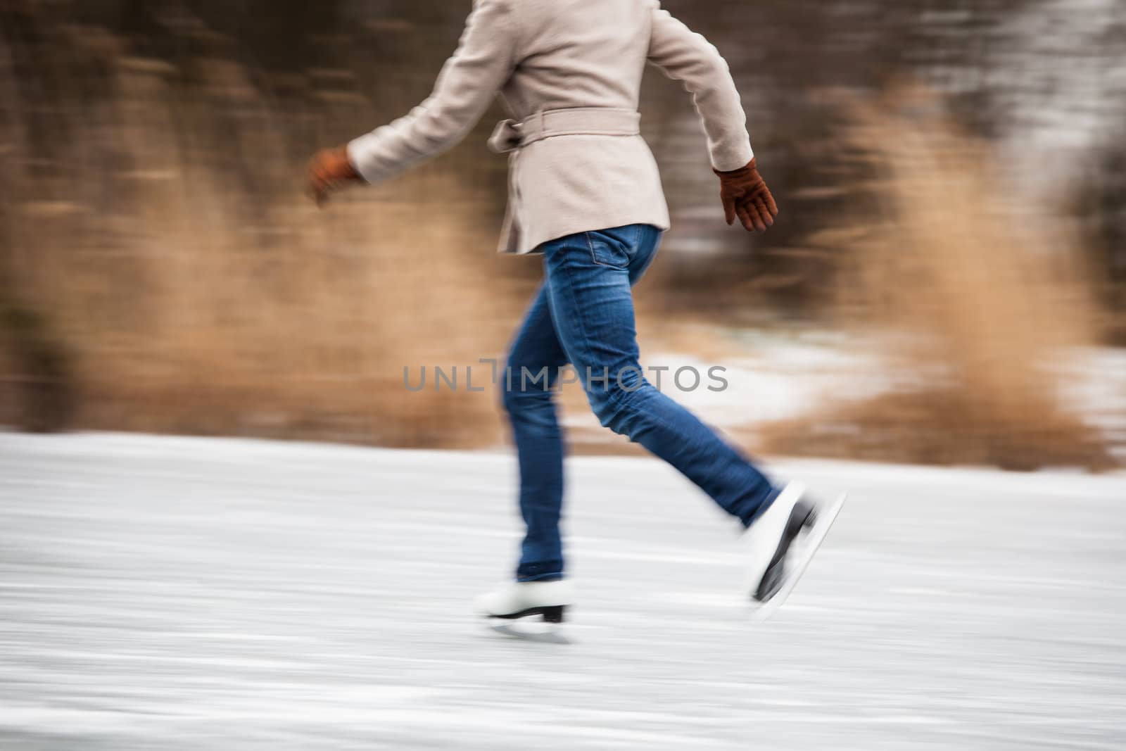 Young woman ice skating outdoors on a pond on a freezing winter day (motion blurred image)