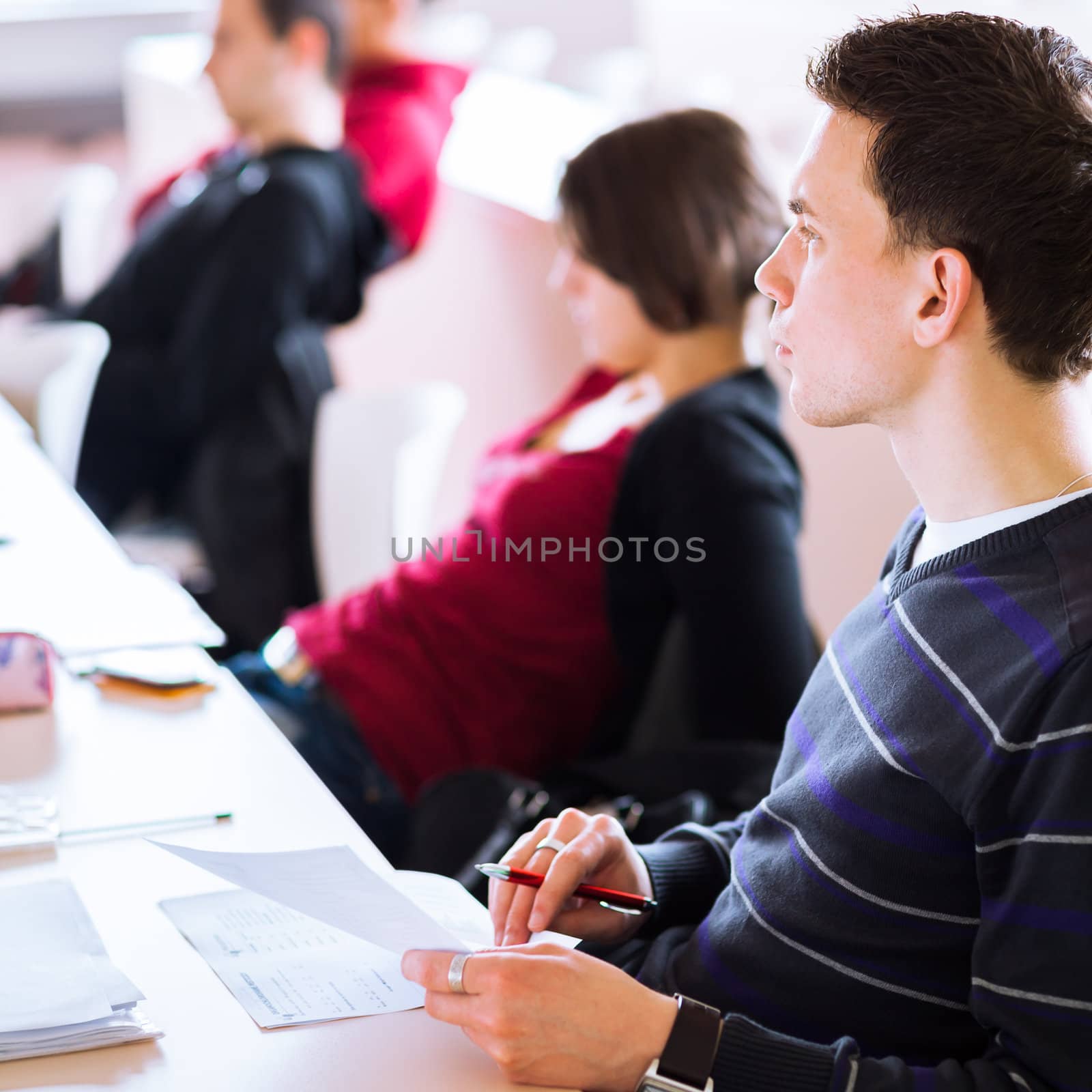 young, handsome male college student sitting in a classroom full by viktor_cap