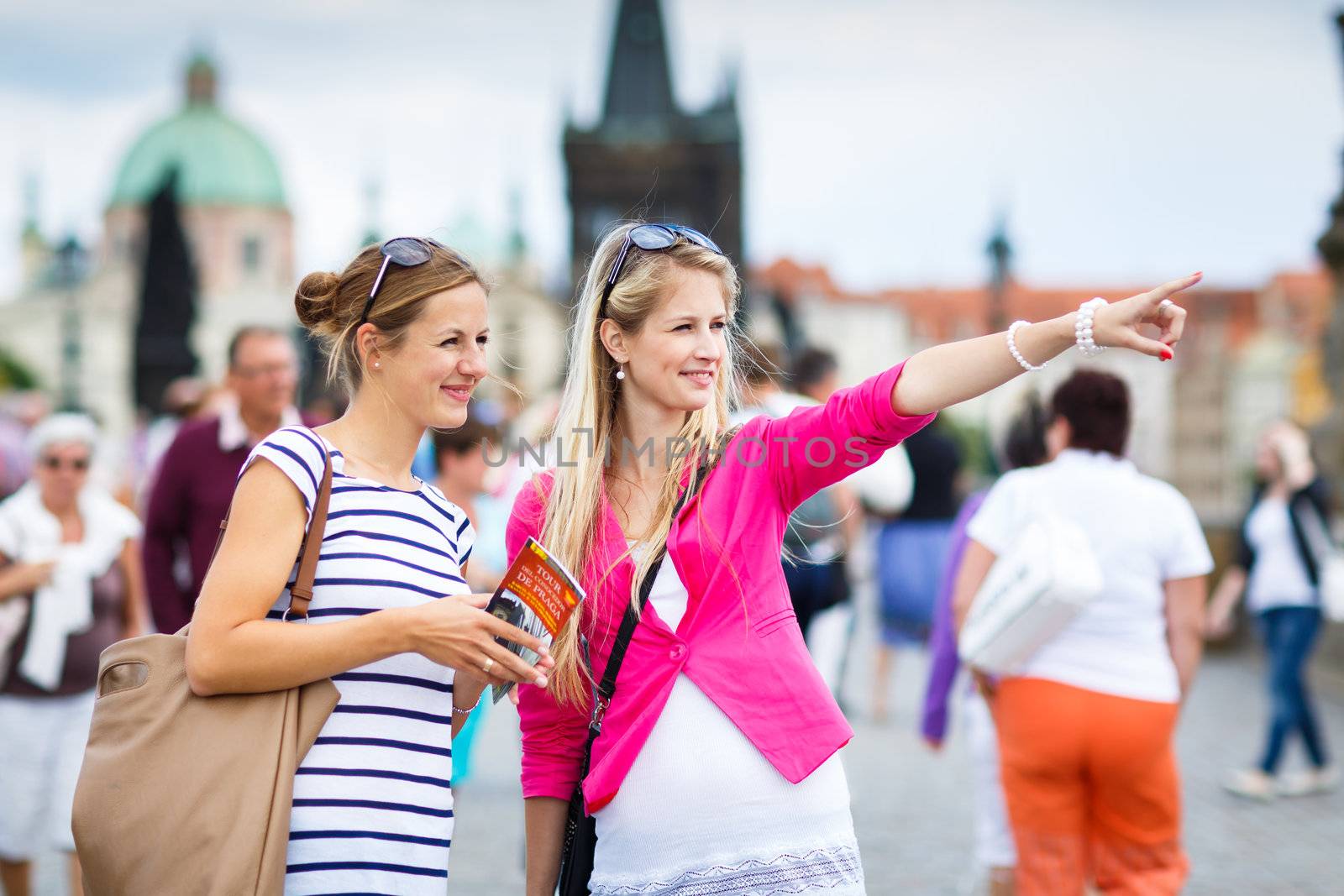 Two female tourists walking along the Charles Bridge while sightseeing in Prague, the historical capital of the Czech Republic (color toned image; shallow DOF)