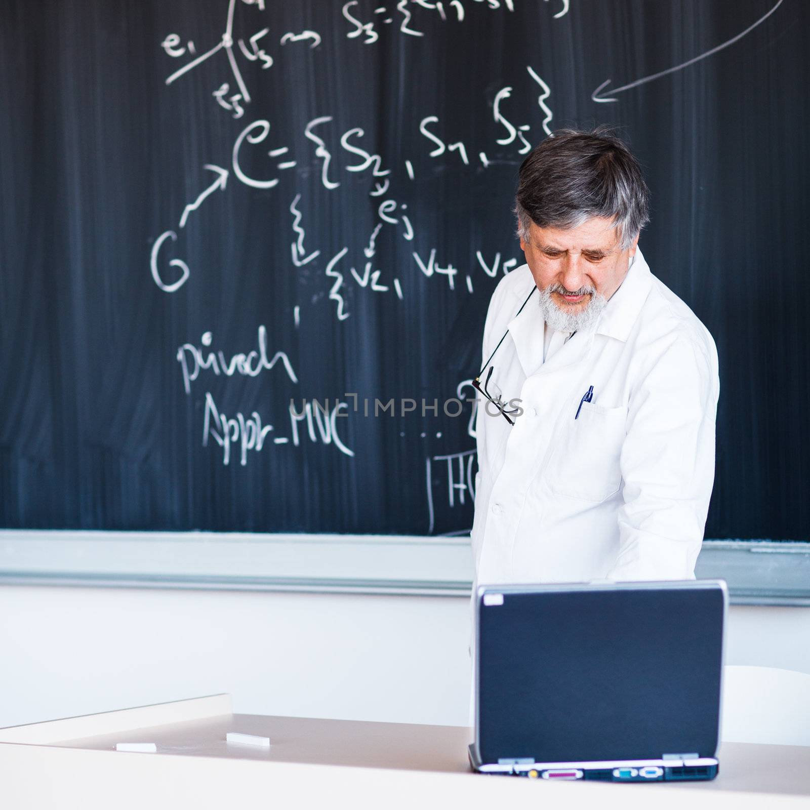 Senior chemistry professor writing on the board while having a c by viktor_cap