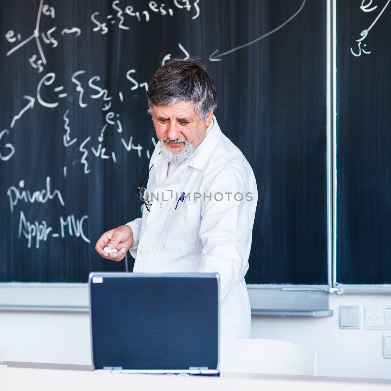 Senior chemistry professor writing on the board while having a c by viktor_cap