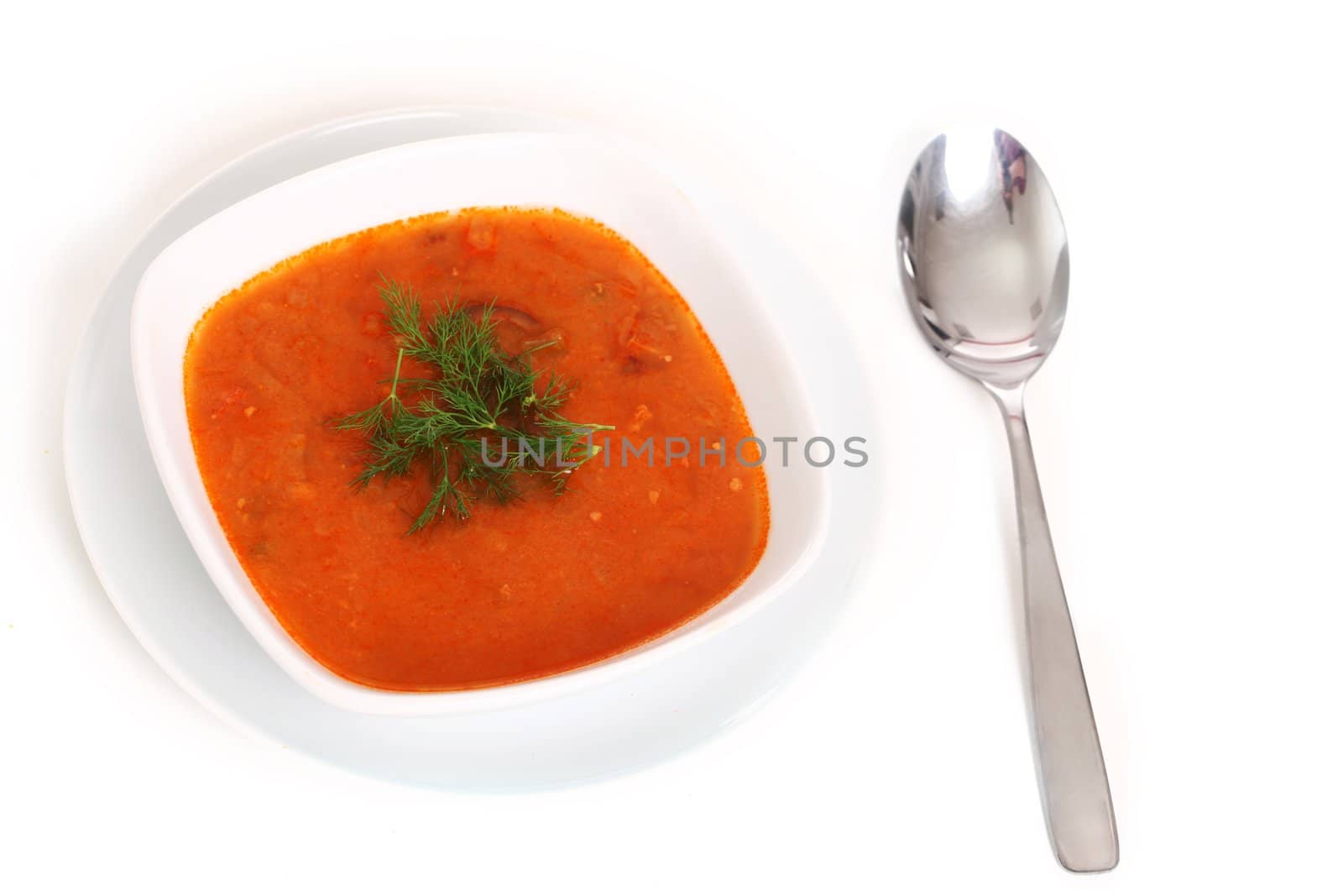 Image of bowl of hot red soup and silver spoon isolated on white background