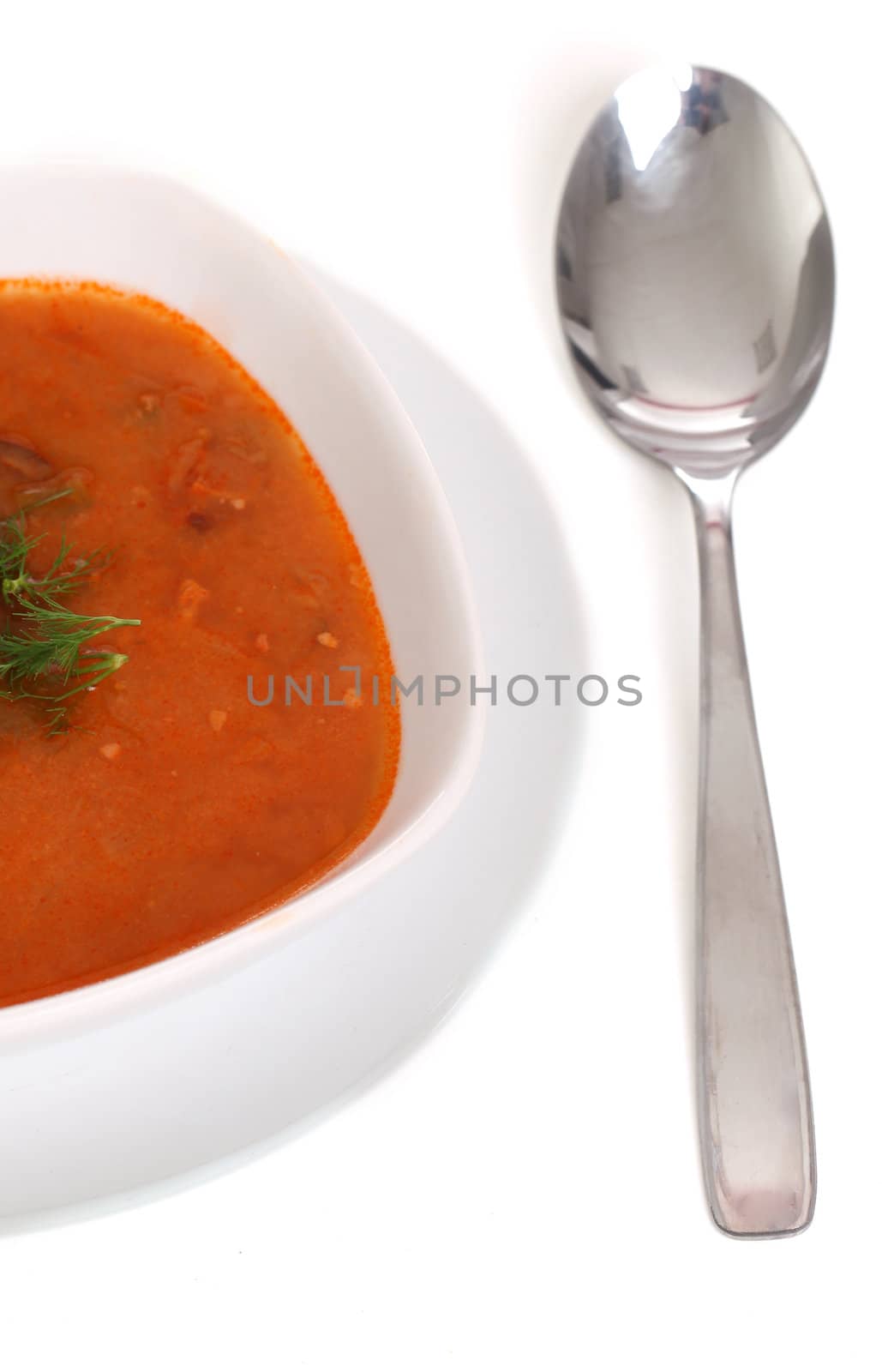 Image of bowl of hot red soup and silver spoon isolated on white background