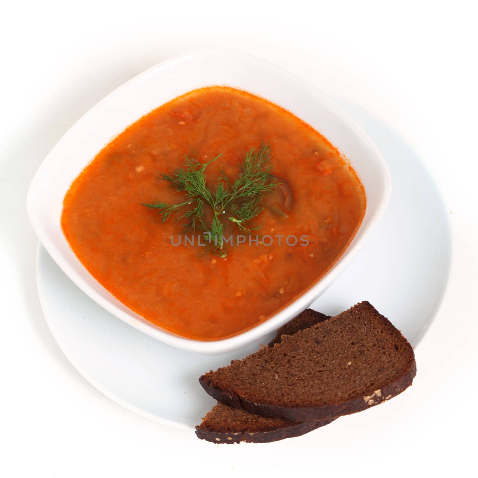 Image of bowl of hot red soup and piece of black bread isolated on white background