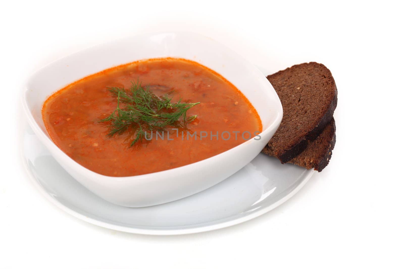 Image of bowl of hot red soup and piece of black bread isolated on white background