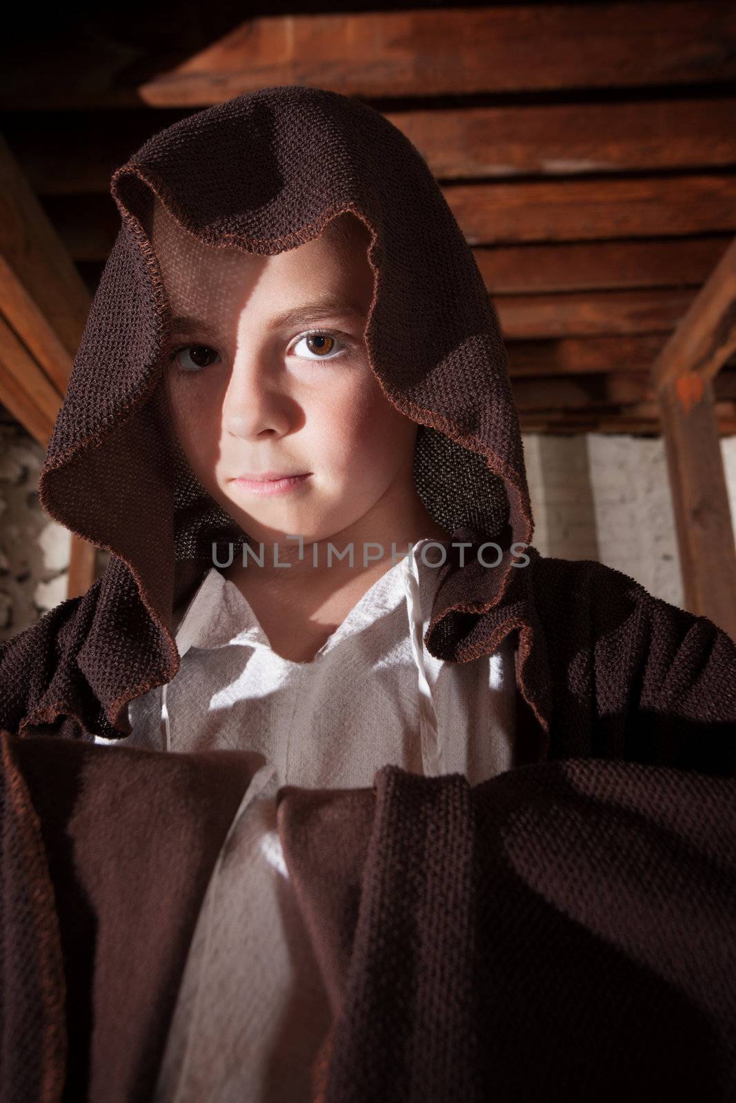 Young magician with folded arms hidden in his cloak