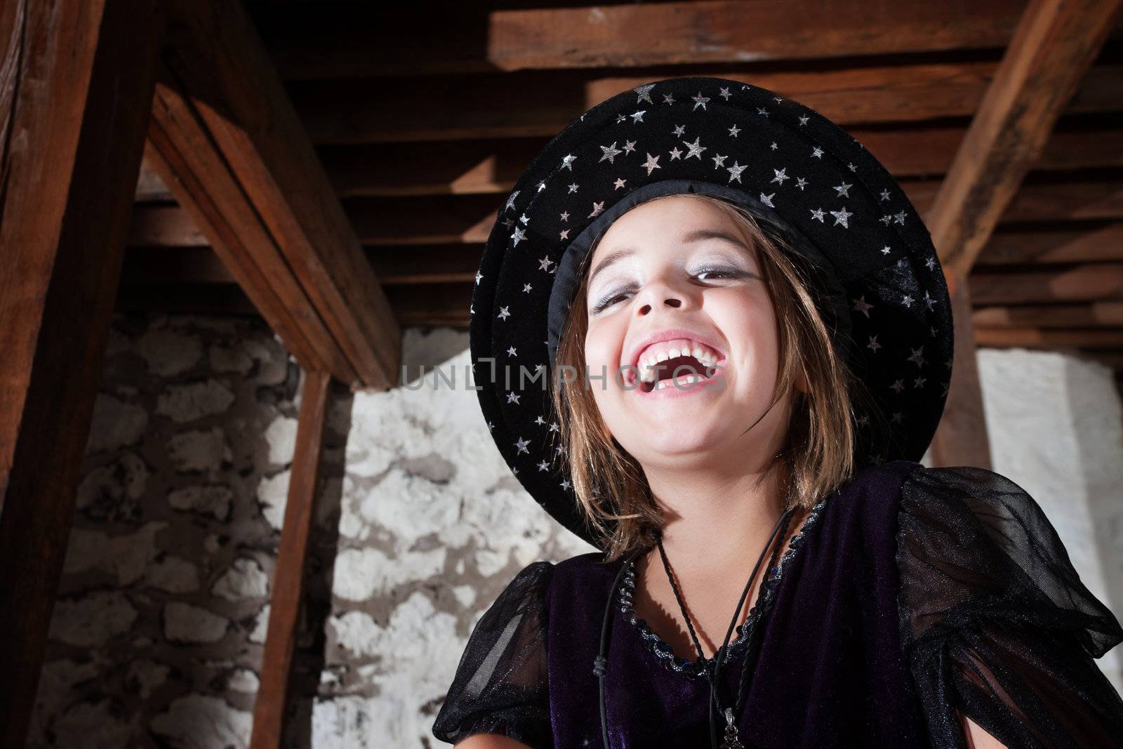 Laughing European child dressed as a witch indoors