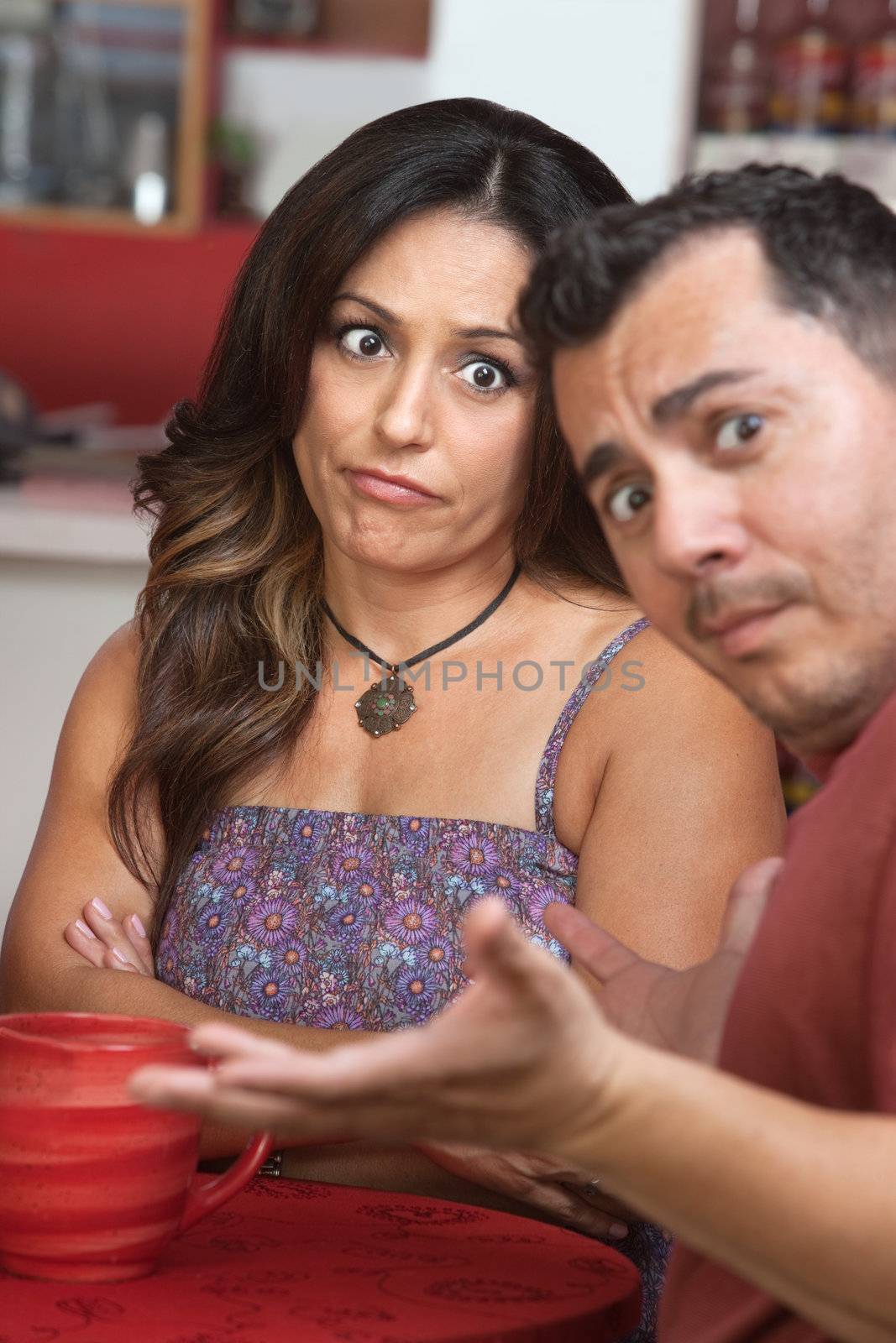 Skeptical Latino woman sitting with man at table