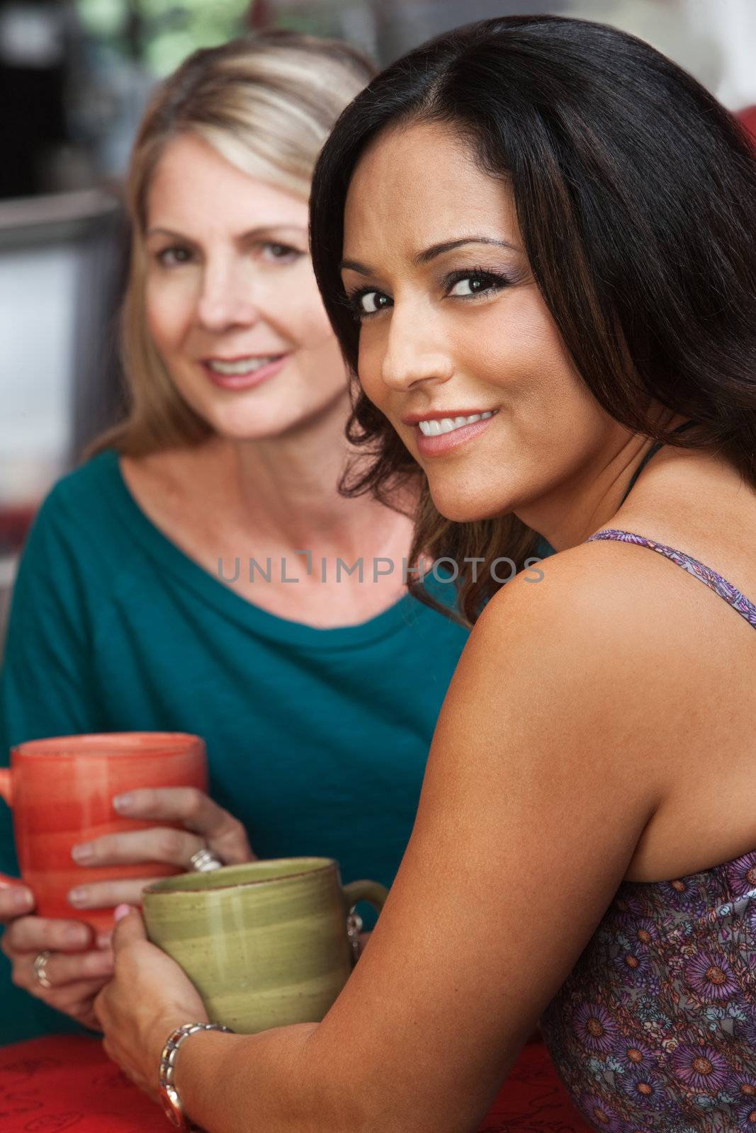 Sexy mature Native American woman sitting with blond friend in cafe