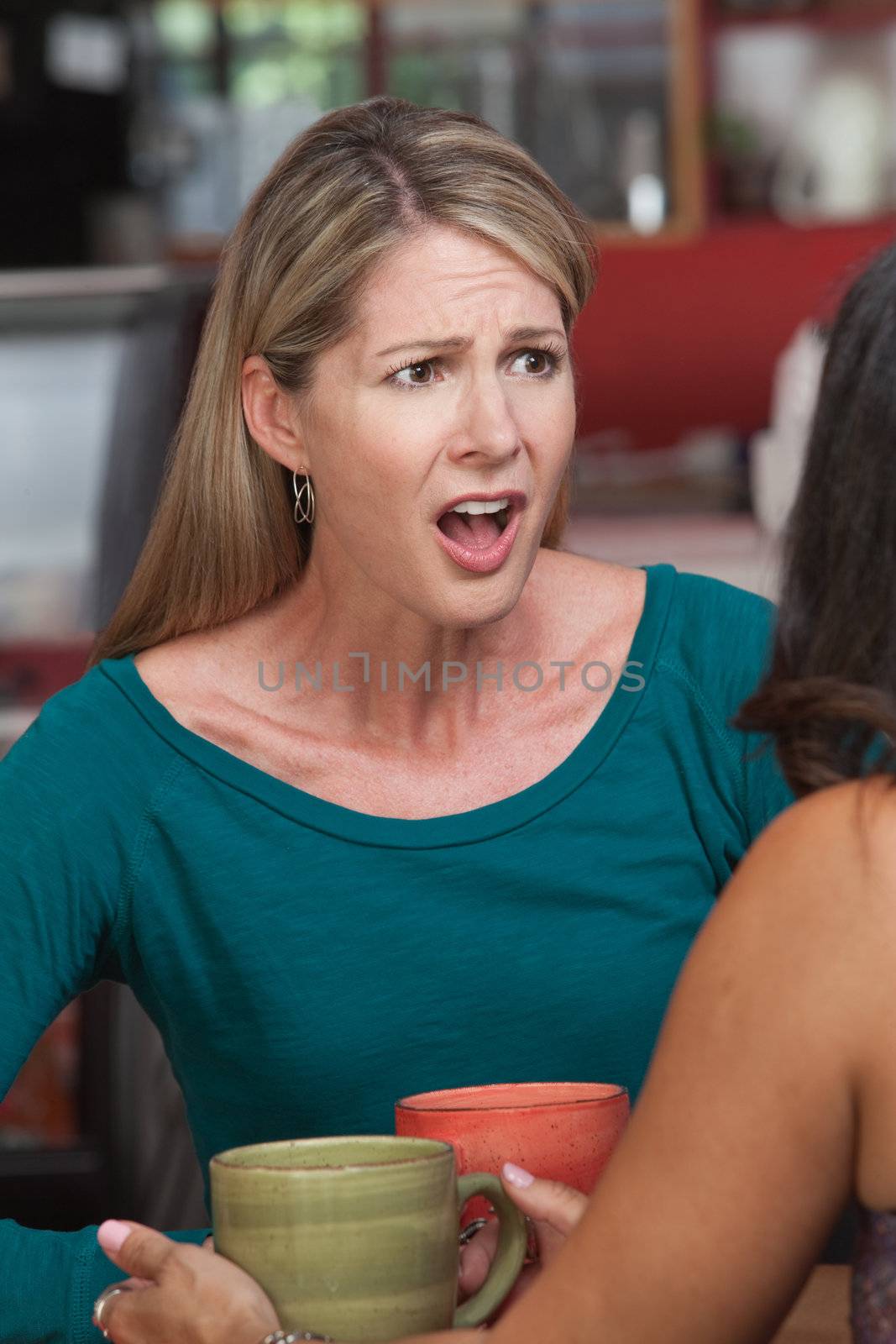 Insulted Caucasian woman across from friend in restaurant