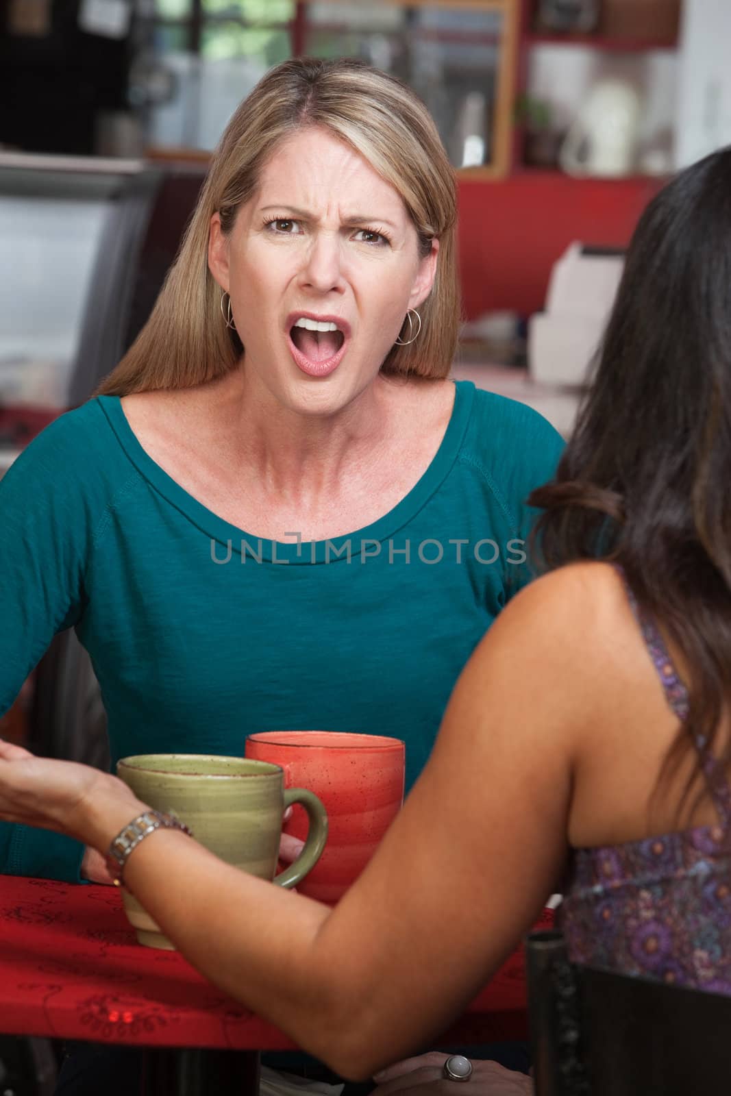 Outraged European woman across from person in a coffeehouse