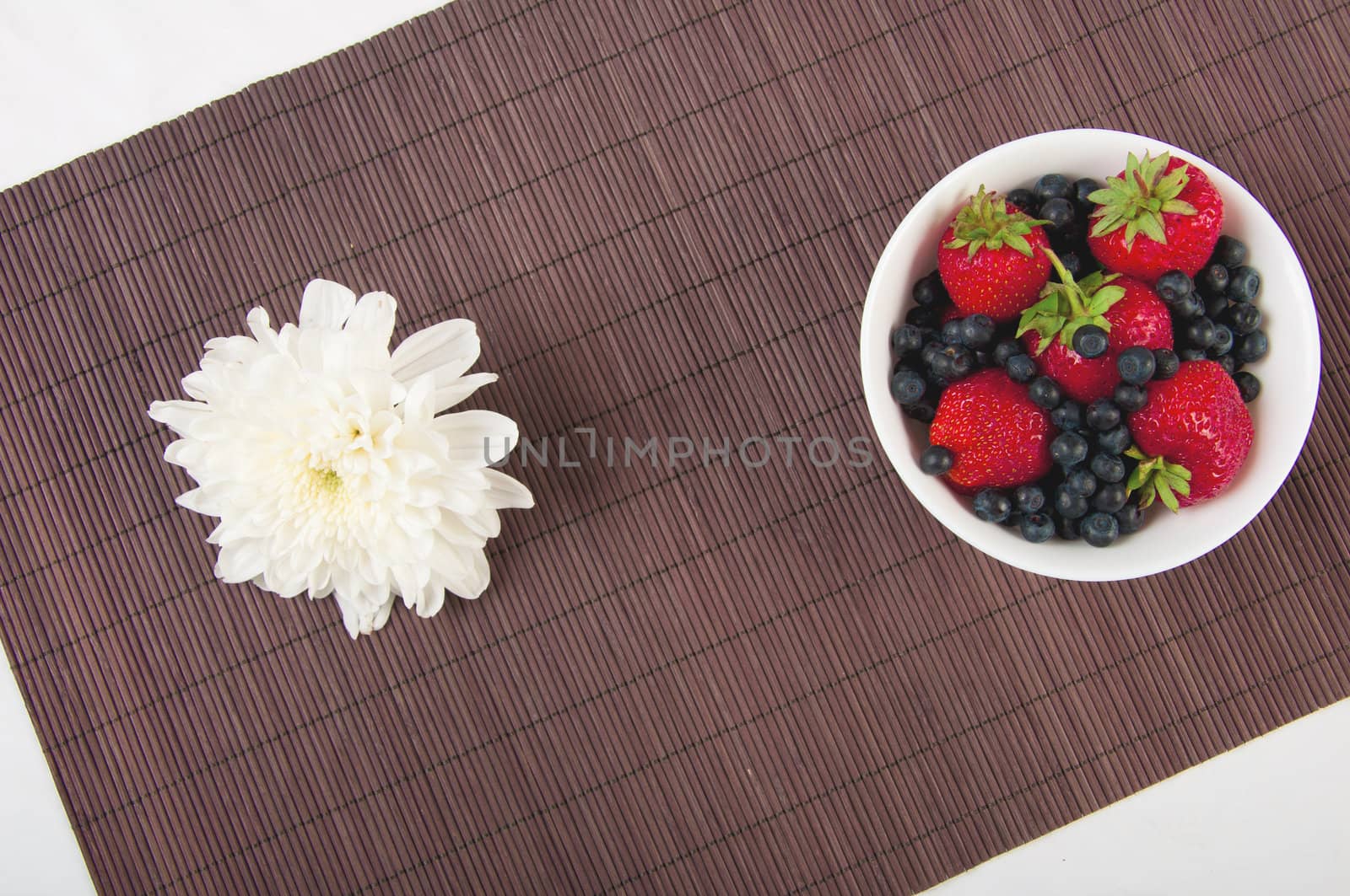 strawberries, bilberry and flower on bamboo tablecloth, still life