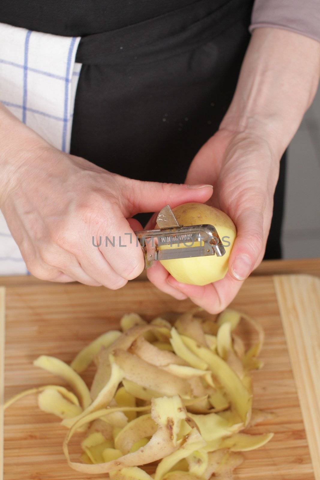 Peeling a potato with peeler in a kitchen