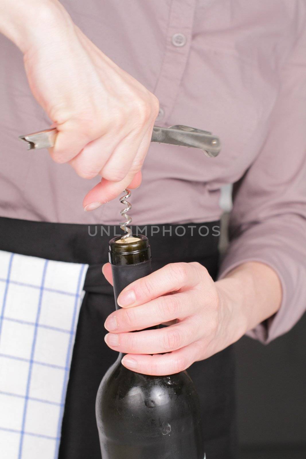 Opening a wine bottle with corkscrew in a kitchen