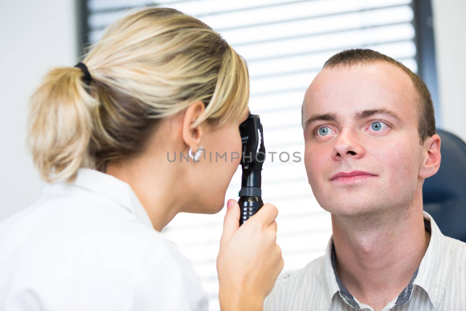 Optometry concept - handsome young man having her eyes examined by an eye doctor