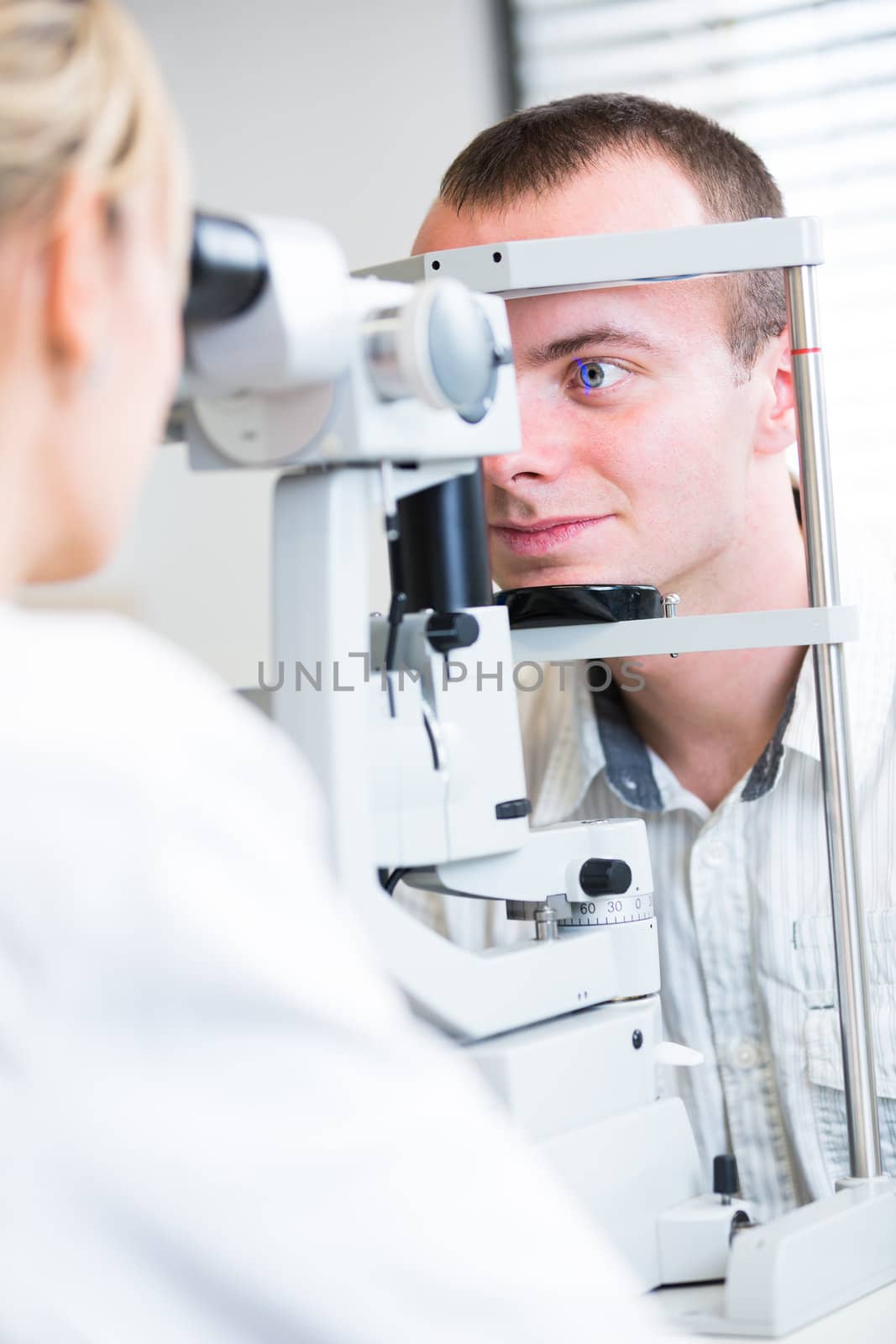 optometry concept - handsome young man having her eyes examined  by viktor_cap