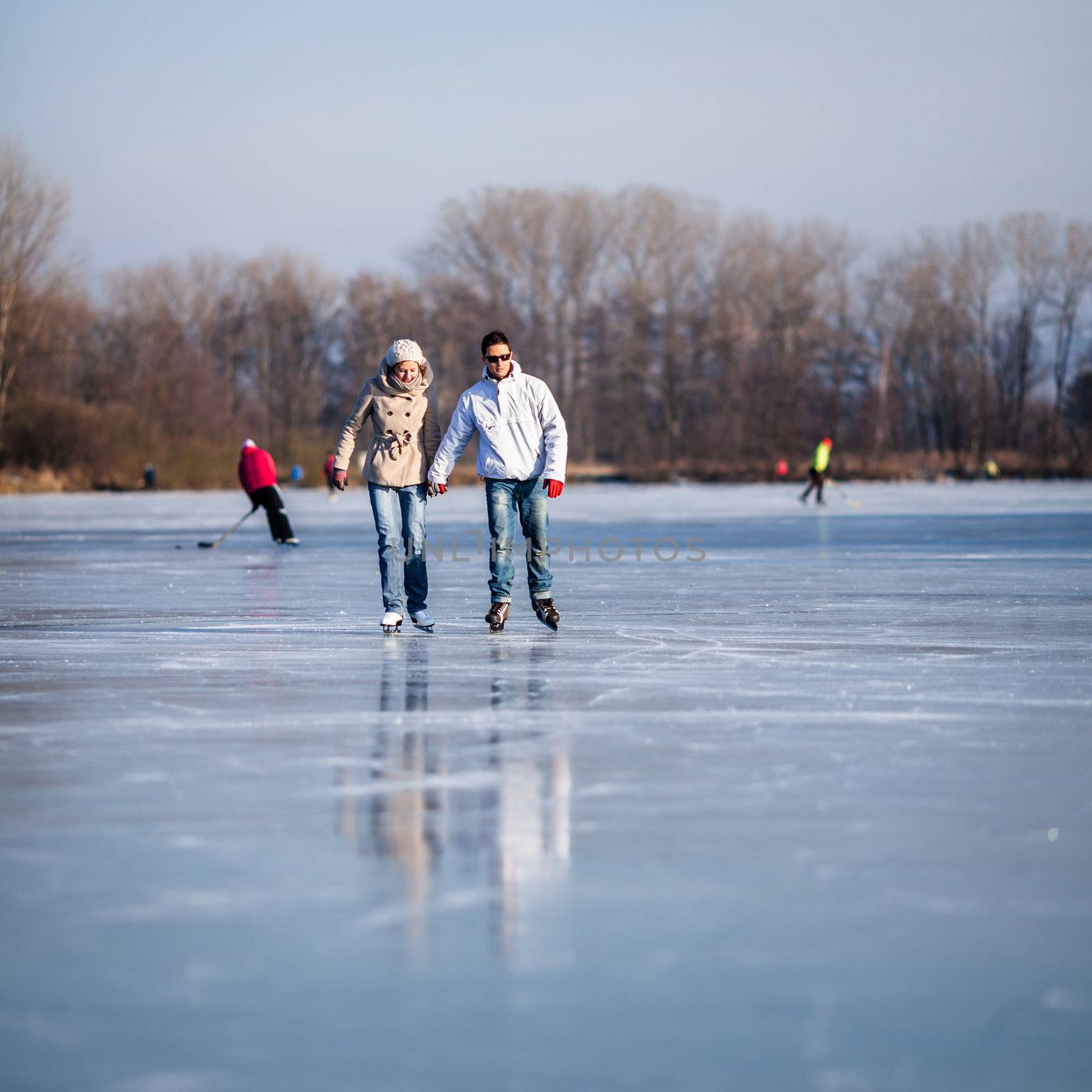 Couple ice skating outdoors on a pond on a lovely sunny winter day