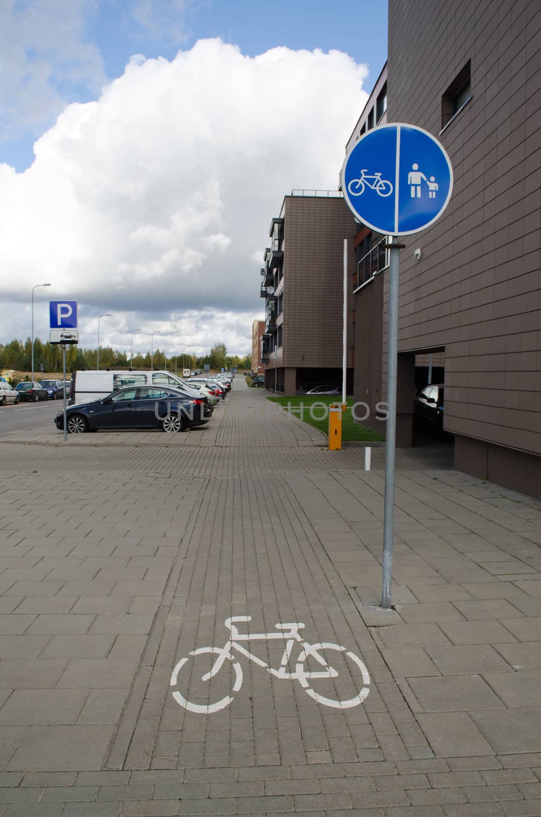 pedestrian footpath walkway bicycle way signs between modern new flat block houses and cars in parking.
