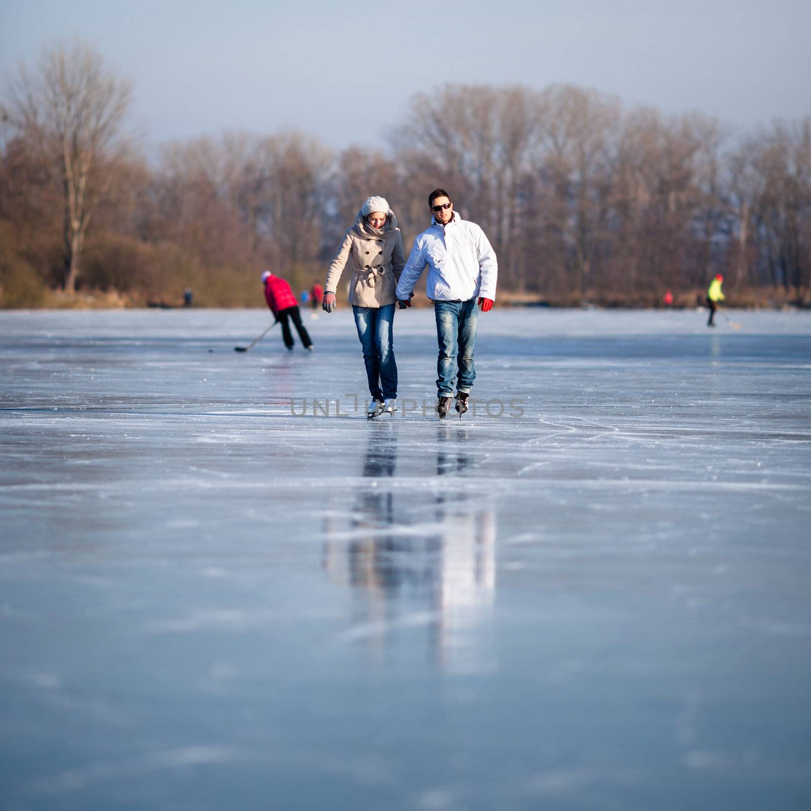 Couple ice skating outdoors on a pond on a lovely sunny winter day