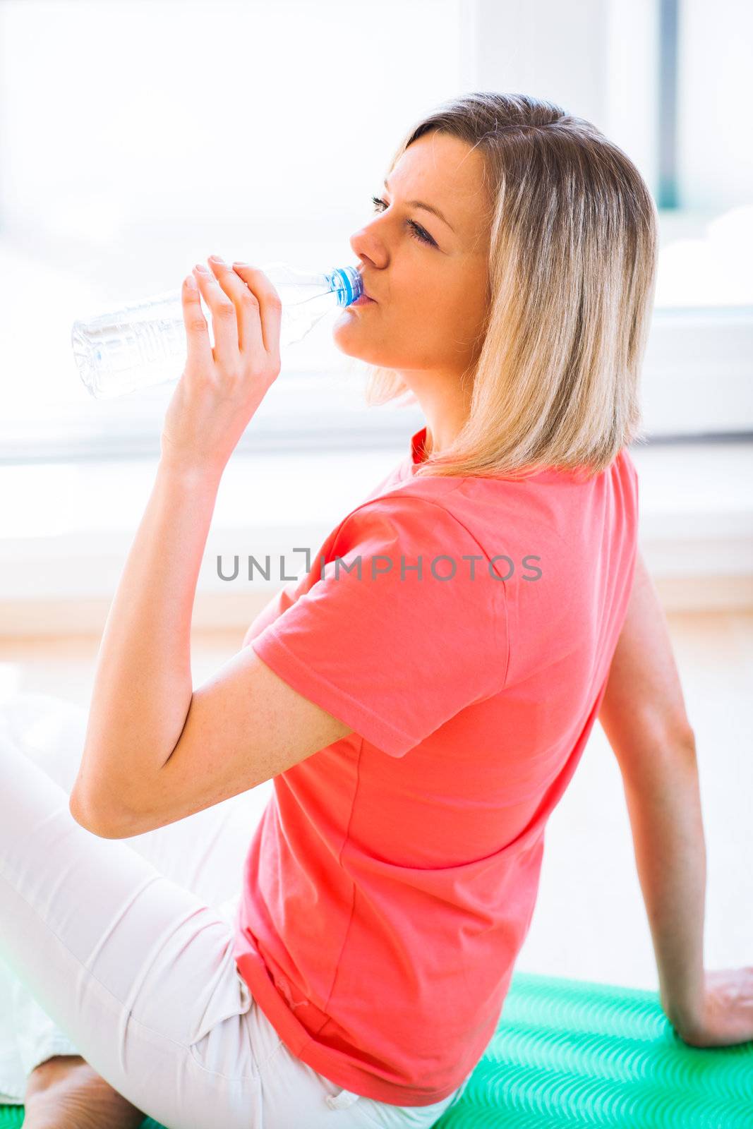 Pretty young woman refreshing during workout at home