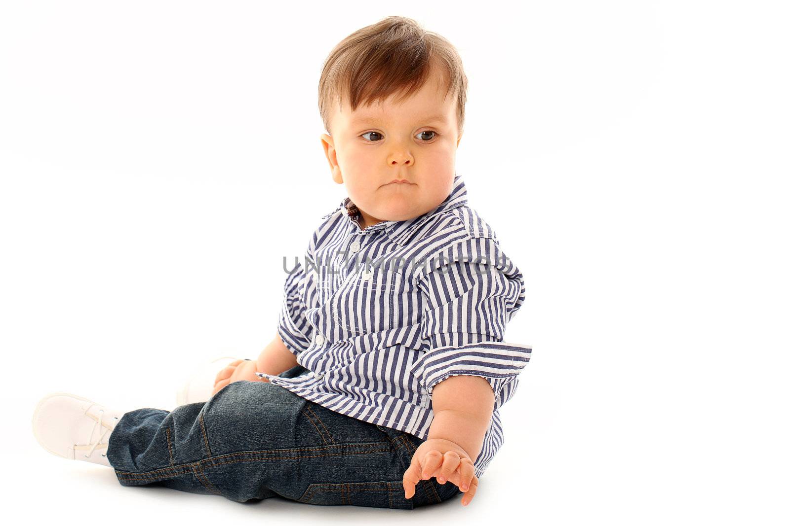 Beautiful serious little boy in jeans isolated over white background