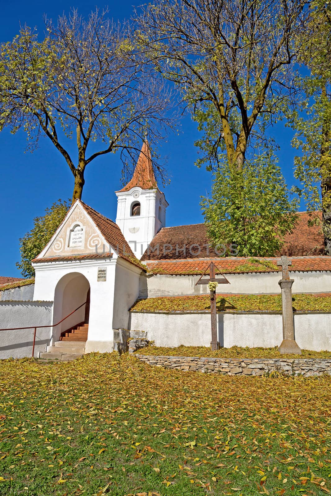 Old white church surrounded by walls in autumn