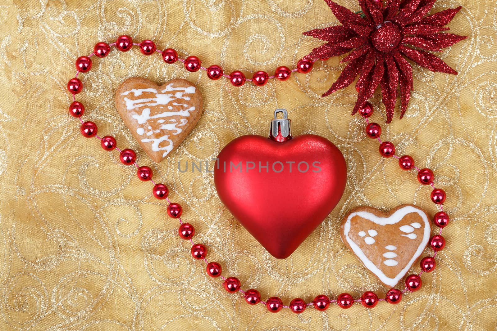 red heart with jewelery and gingerbread on christmas table cloth